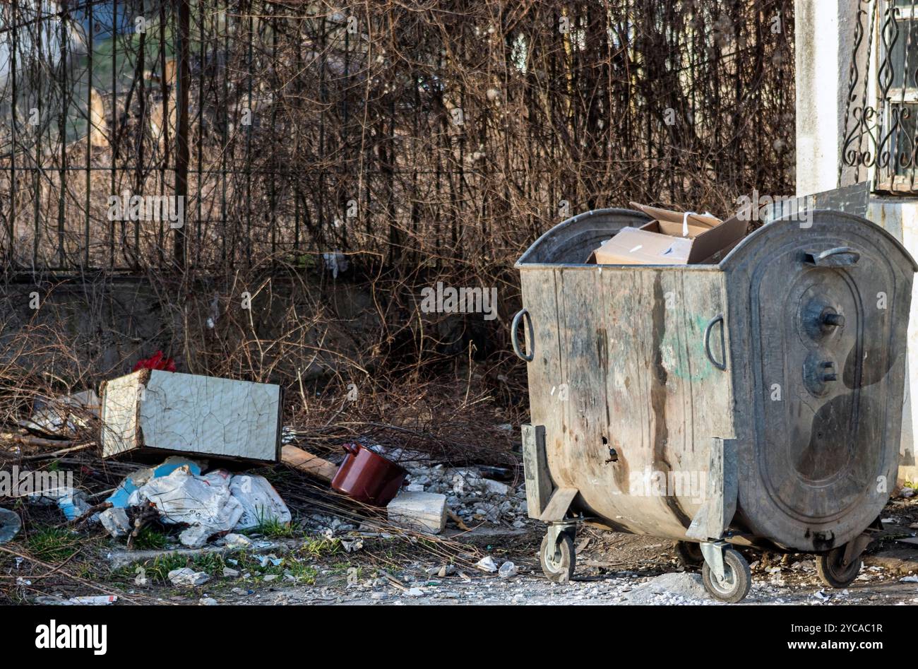 Un contenitore pieno di rifiuti vicino a un'area di riciclaggio Foto Stock
