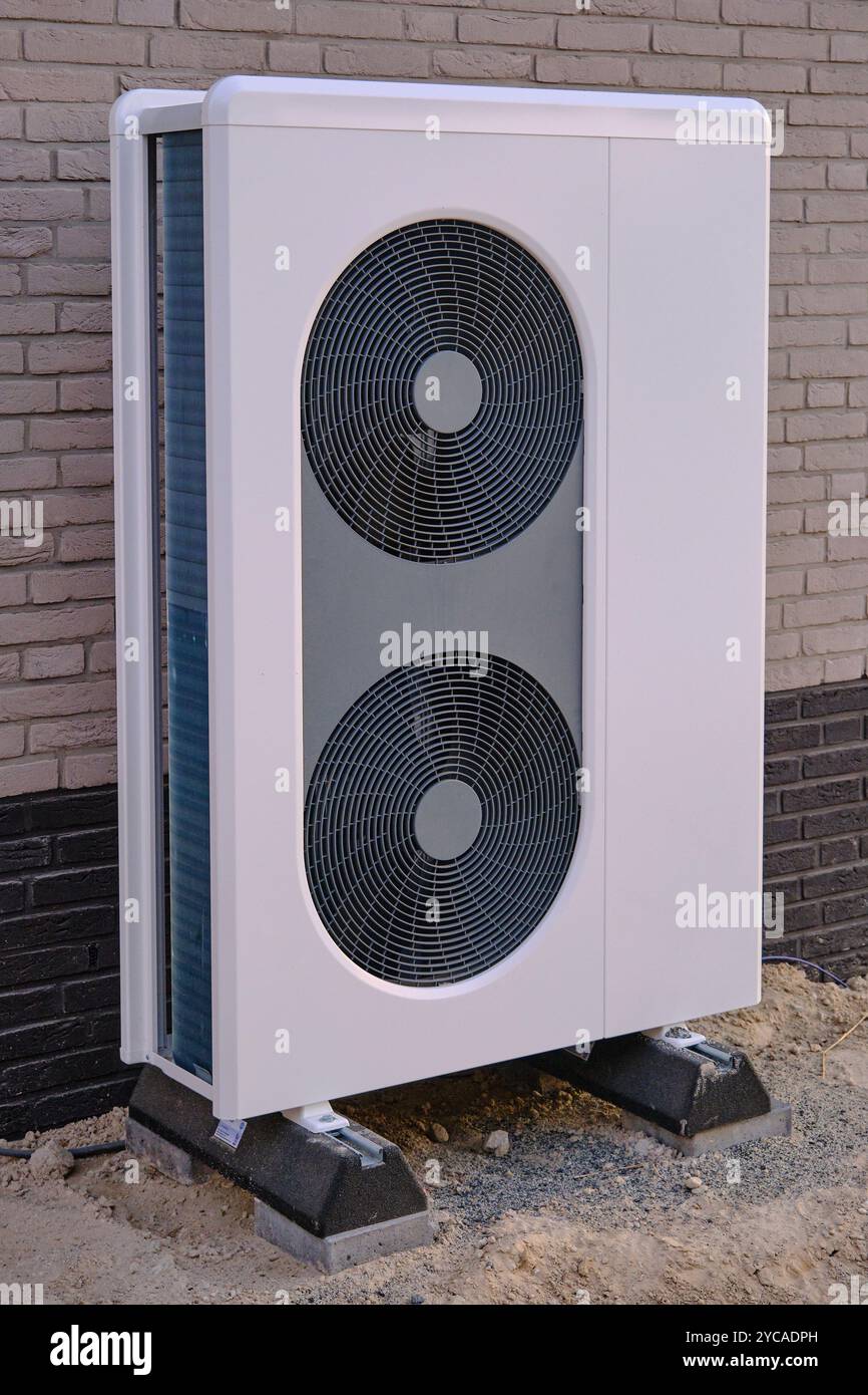 grande e moderna pompa di calore ad aria montata all'esterno di una casa, che dimostra una tecnologia efficiente dal punto di vista energetico per il riscaldamento e il raffreddamento in un ambiente sostenibile, e Foto Stock