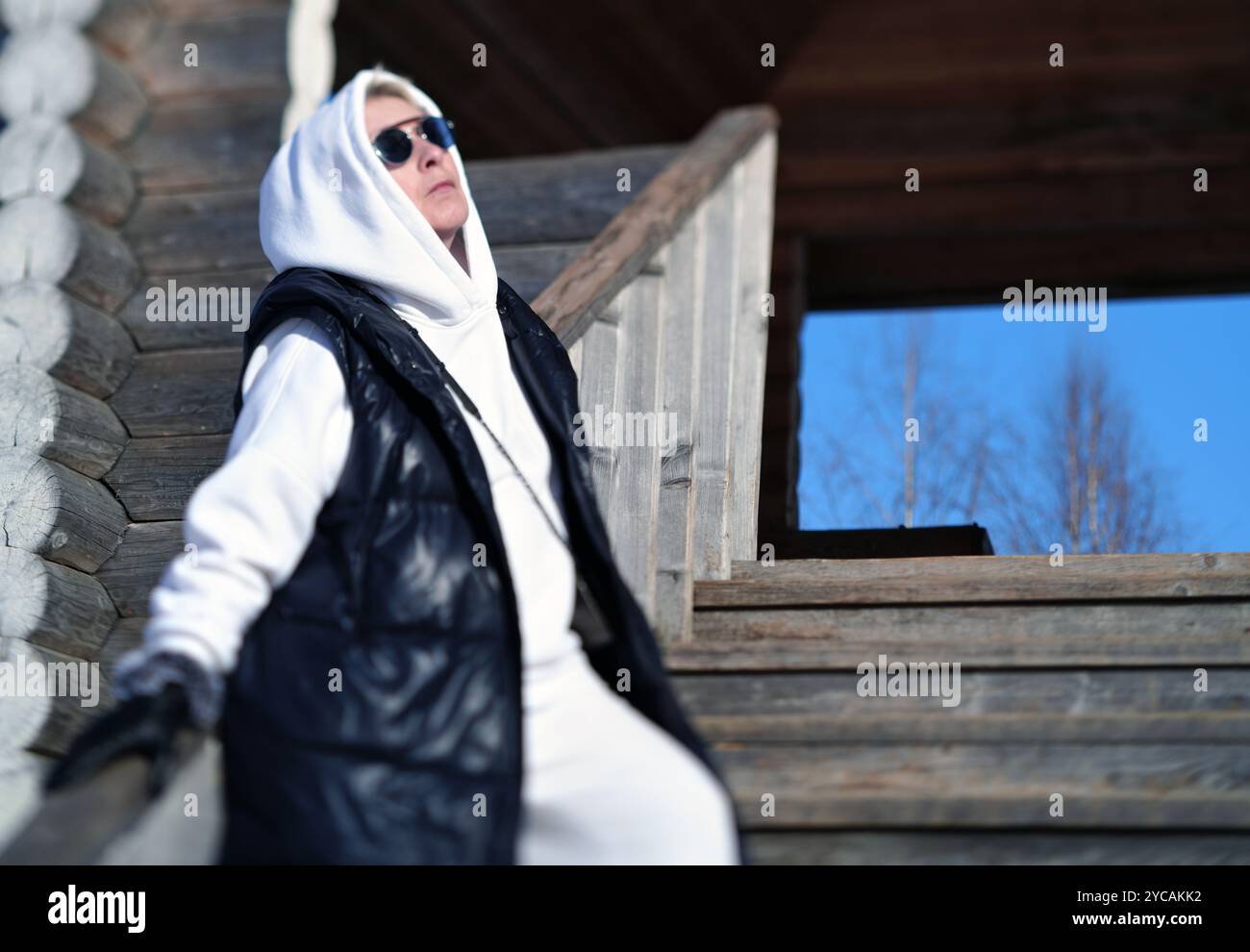 una donna che indossa occhiali da sole e cappuccio abbronzarsi in inverno, con scatti all'aperto inclinabili Foto Stock
