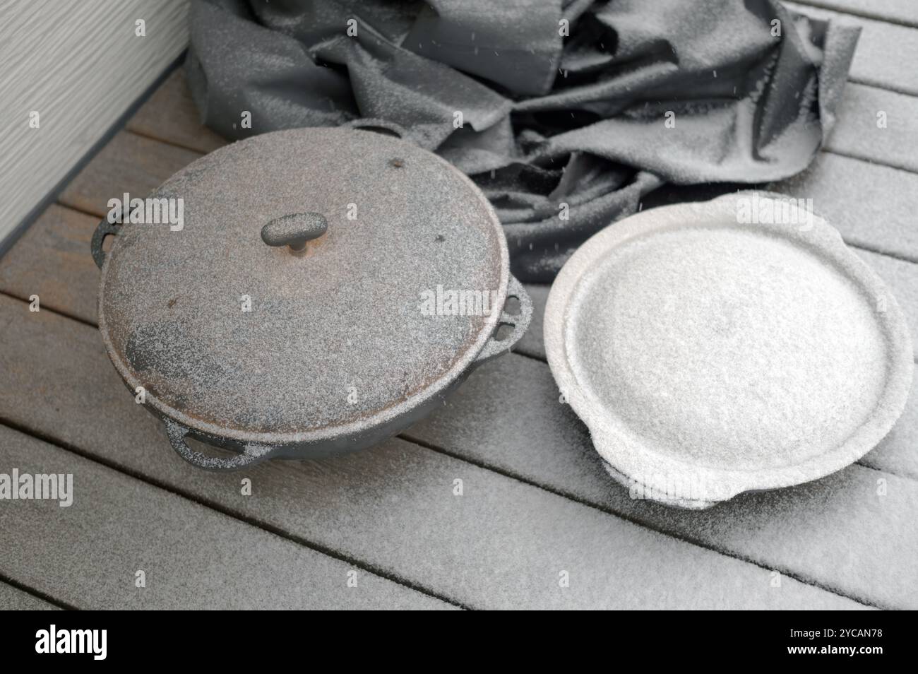 utensili da cucina in ghisa lasciati all'esterno sotto lo snowall, shot diurno in inverno Foto Stock