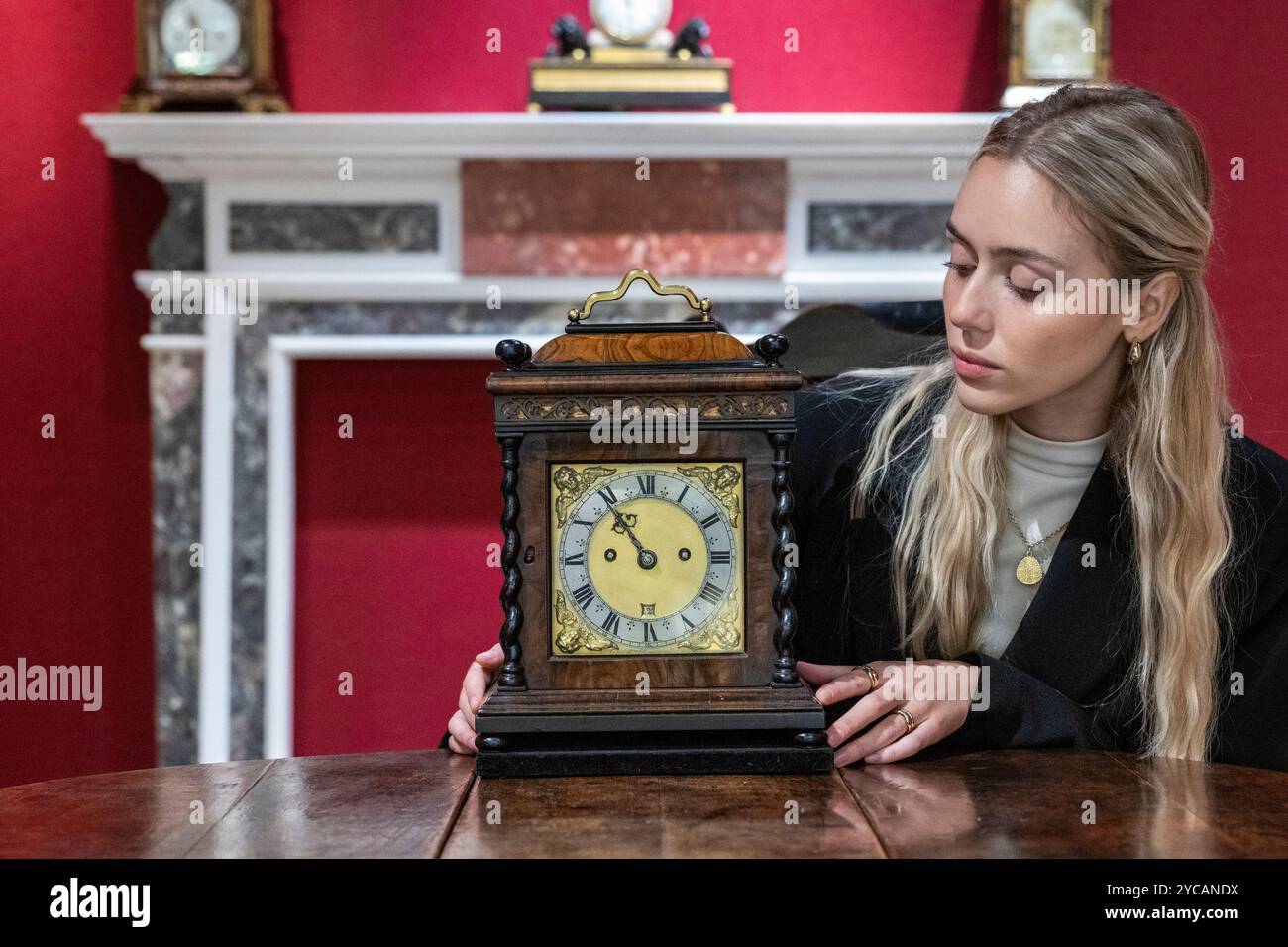 Londra, Regno Unito. 22 ottobre 2024. Un membro dello staff con un orologio da tavolo "Robert Williamson Londini", Charles II, intorno al 1675, presso lo stand Howard Walwyn in anteprima della fiera LAPADA dell'Association of Art & Antiques Dealers. I rivenditori specializzati stanno presentando una vasta gamma di opere d'arte, design e antiquariato con la garanzia di autenticità grazie a un comitato di esperti composto da 70 membri che controlla in anticipo tutto ciò che è in vendita. La fiera si svolge dal 22 al 27 ottobre a Berkeley Square. Crediti: Stephen Chung / Alamy Live News Foto Stock