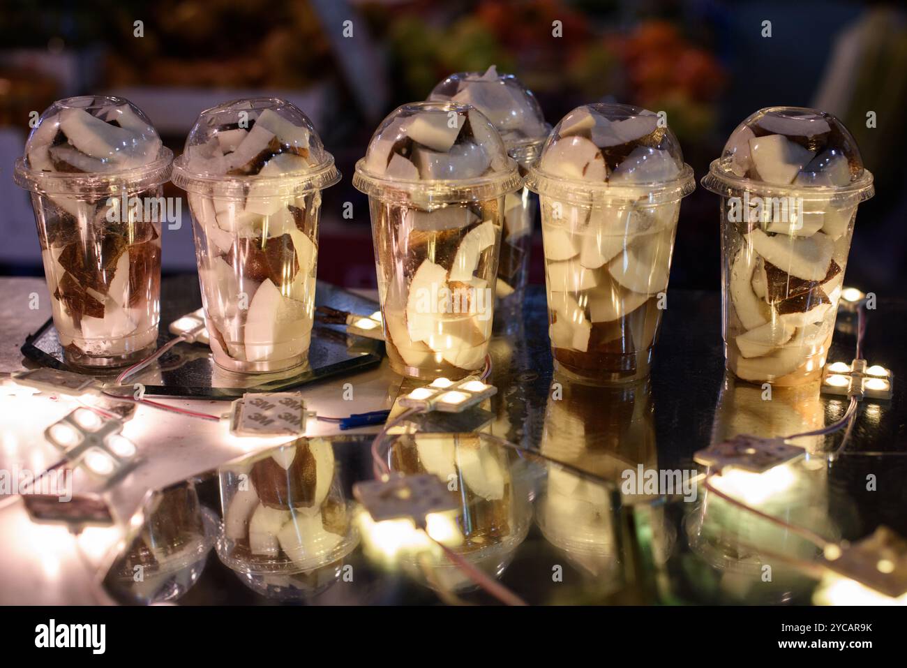 Tazze di plastica riempite con una noce di cocco appena tagliata per frullare e frullati. Foto Stock