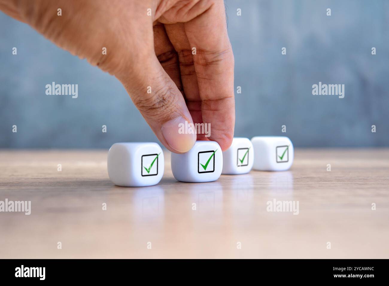 Una mano sta raggiungendo un cubo bianco con un segno di spunta. Concetto di conformità aziendale. Foto Stock