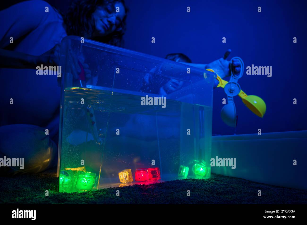 Bambino e terapista in camera stimolante sensoriale, Black snoezelen. Bambino autistico che gioca con il terapista durante la sessione di terapia occupazionale. Foto Stock