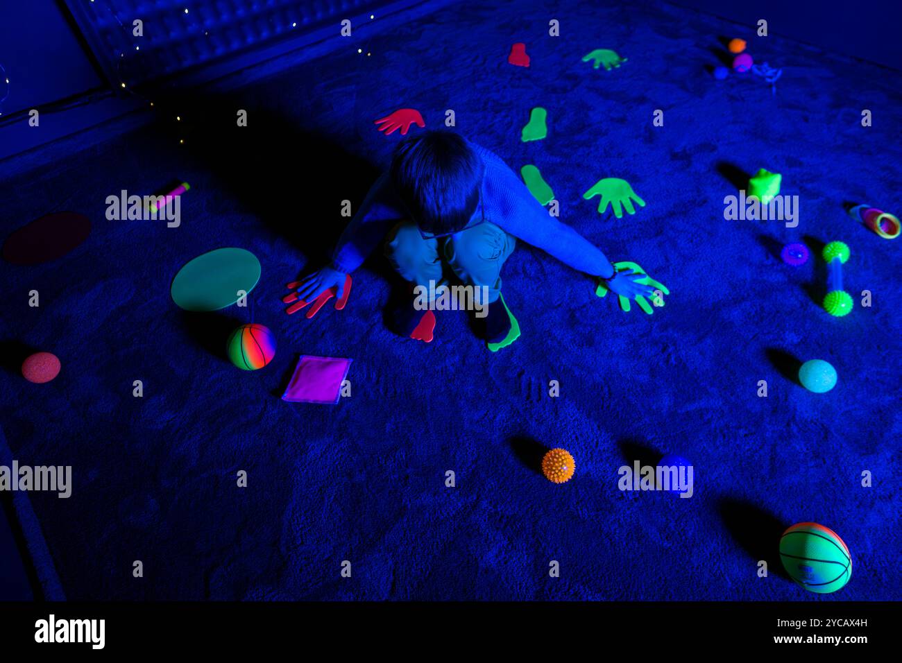 Bambino in sala terapia stimolante sensoriale, nero snoezelen. Bambino autistico che gioca durante la sessione di terapia. Terapia occupazionale. Stimolo sensoriale terapeutico Foto Stock
