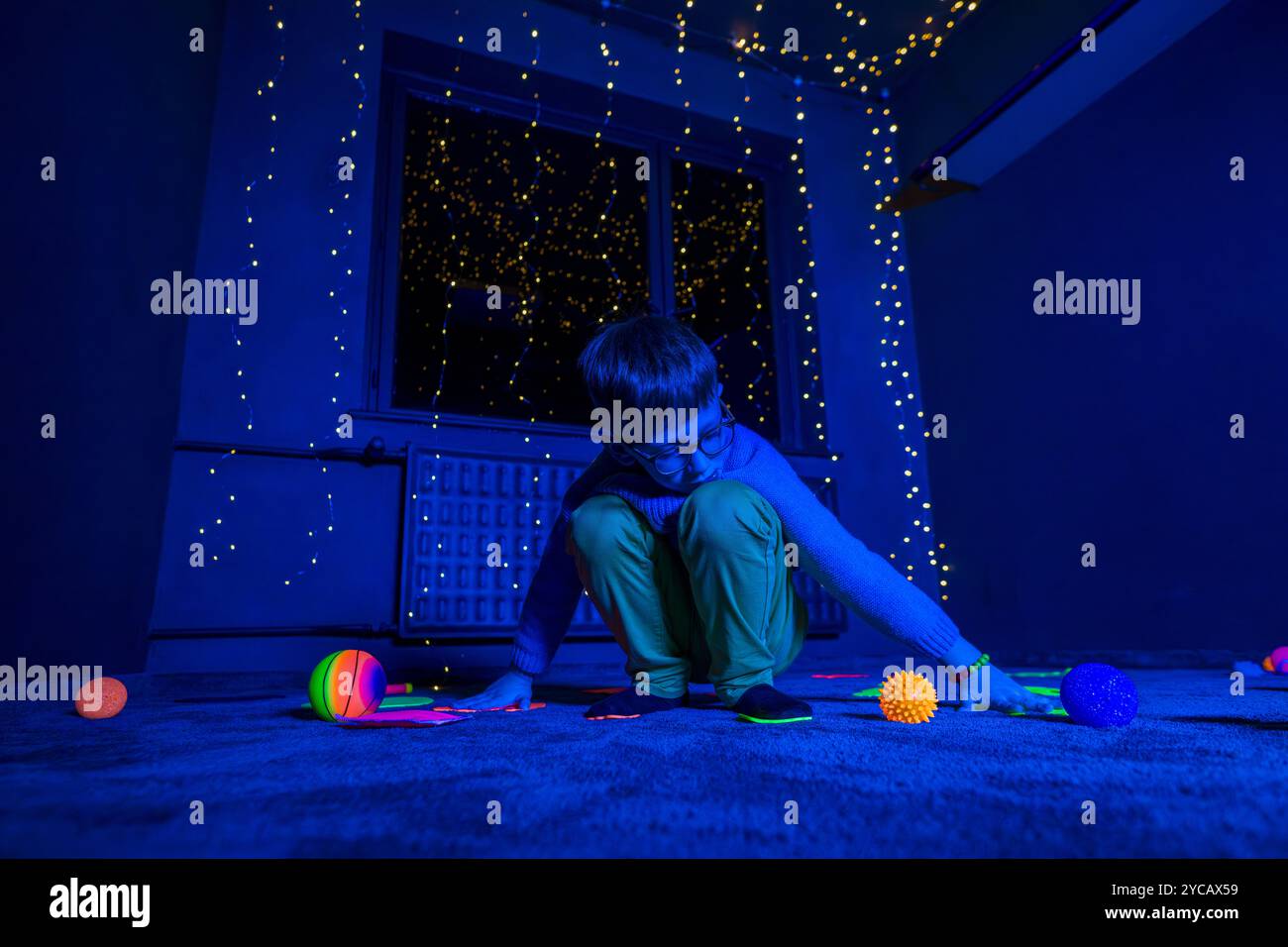 Bambino in sala terapia stimolante sensoriale, nero snoezelen. Bambino autistico che gioca durante la sessione di terapia. Terapia occupazionale. Stimolo sensoriale terapeutico Foto Stock