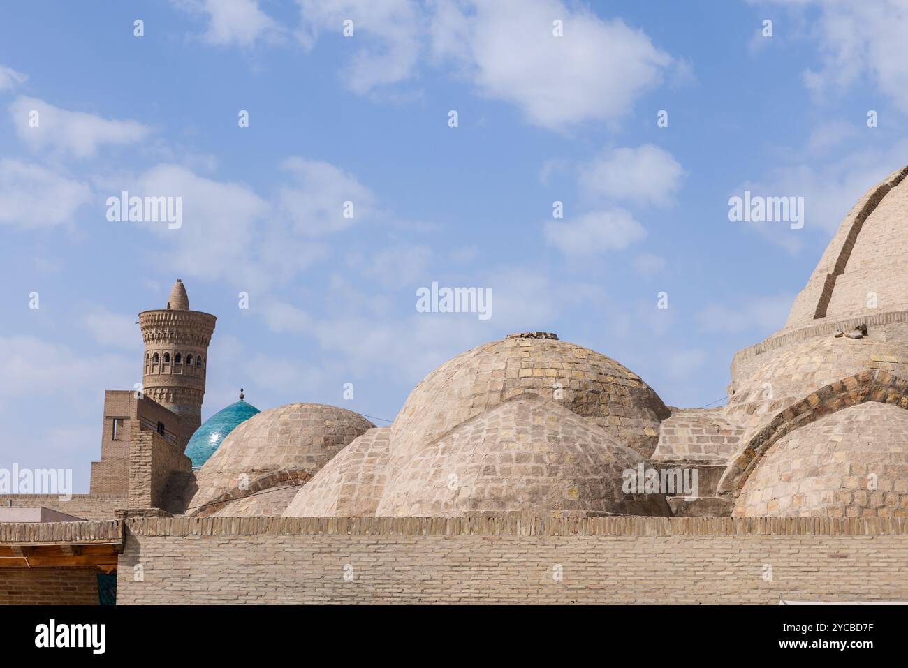 Skyline della città vecchia di Bukhara, Uzbekistan. Antiche cupole e minareti sono sotto il cielo azzurro nuvoloso Foto Stock