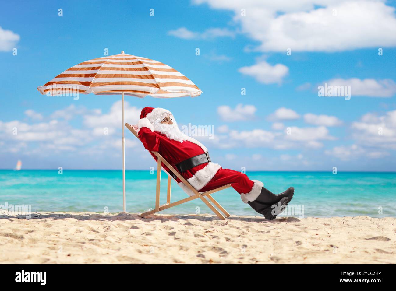 Babbo natale in una vacanza estiva che prende il sole sul mare su una spiaggia sabbiosa Foto Stock