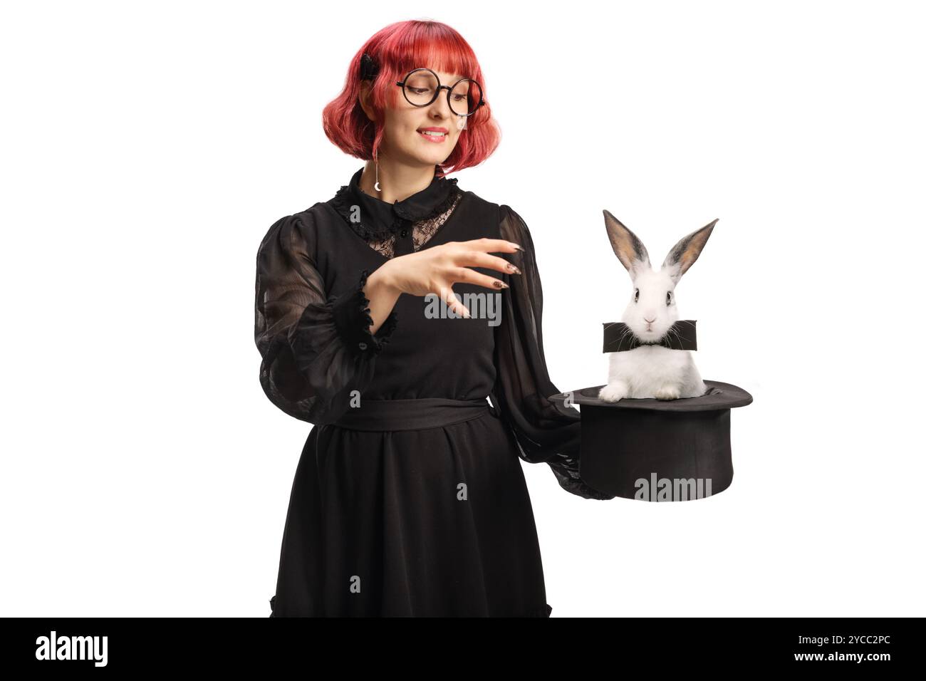 Maga donna con un cappello che esegue un trucco magico con un coniglio isolato su sfondo bianco Foto Stock