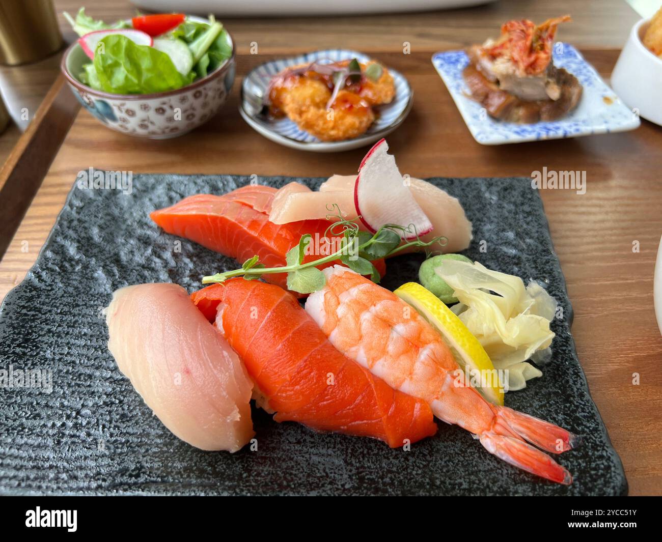 Salmone e tonno sashimi (centro) e sushi insieme (in alto da sinistra) insalata, tempura e okazu in un ristorante di cucina giapponese Foto Stock