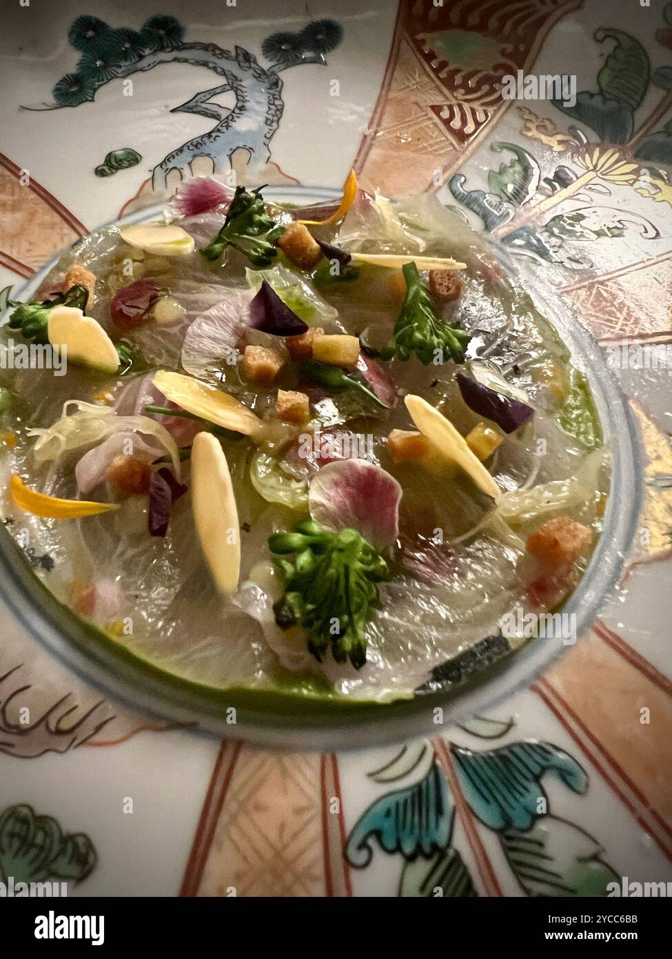Squisito piatto giapponese di sashimi, abilmente organizzato con fette di pesce fresco, mandorle a fette, microgreen e fiori commestibili su un piatto giapponese ornato Foto Stock