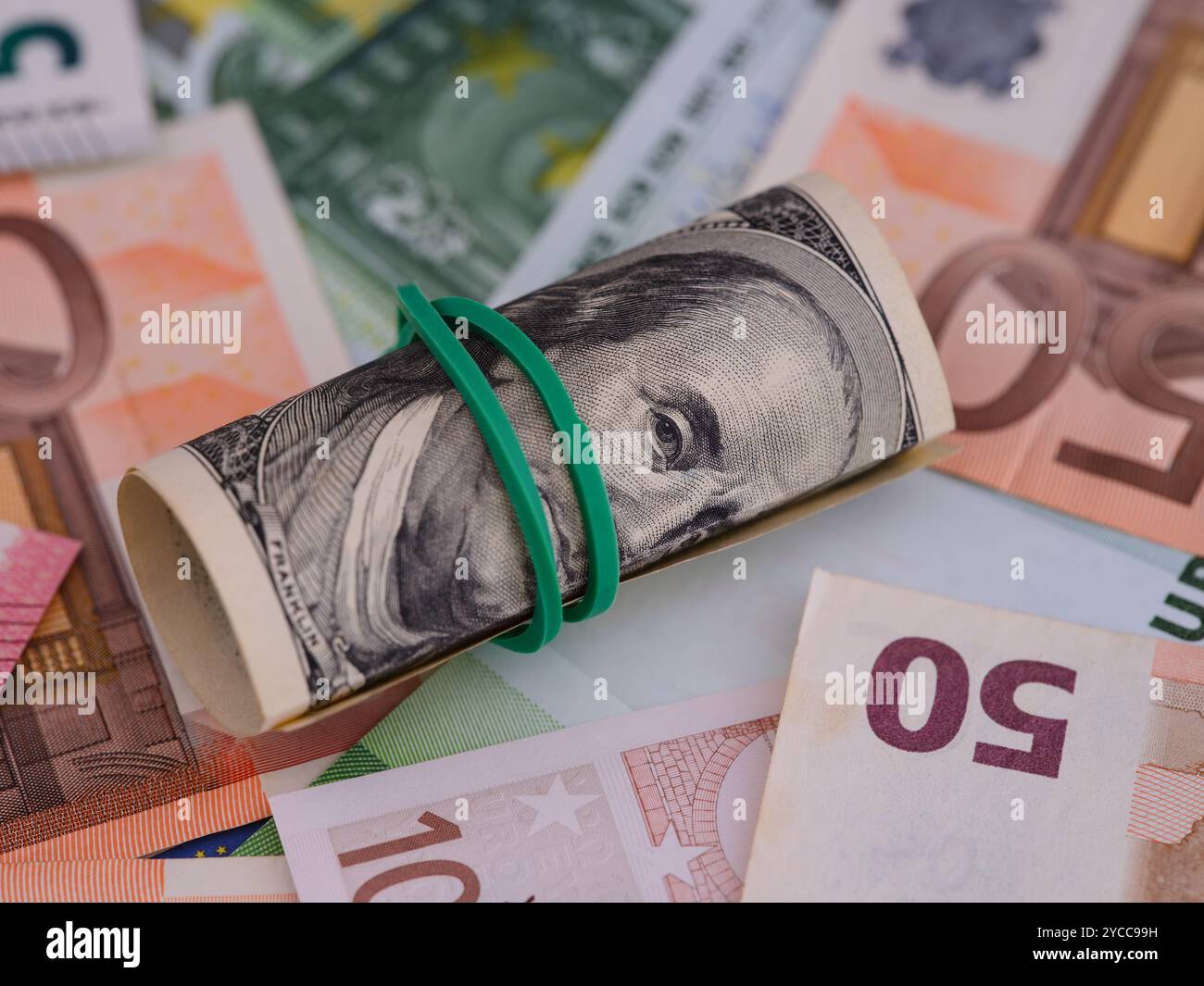 Una pila di banconote da cento dollari che si trovano sullo sfondo delle banconote in euro. Foto Stock