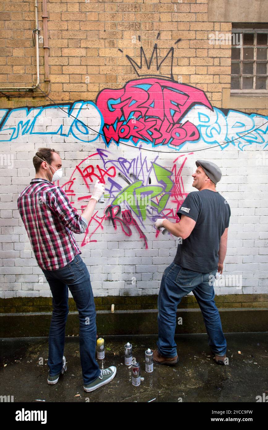 L'artista Rob Wheeler (a destra) disegna disegni durante un corso di graffiti, Regno Unito. Foto Stock