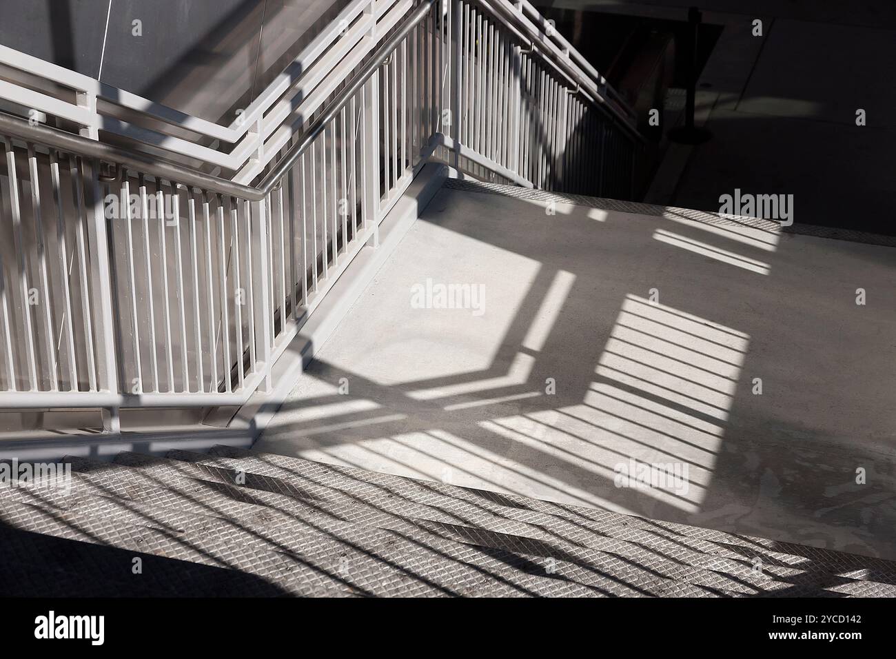 Luci e ombre si fondono su una scala in una stazione ferroviaria. Foto Stock