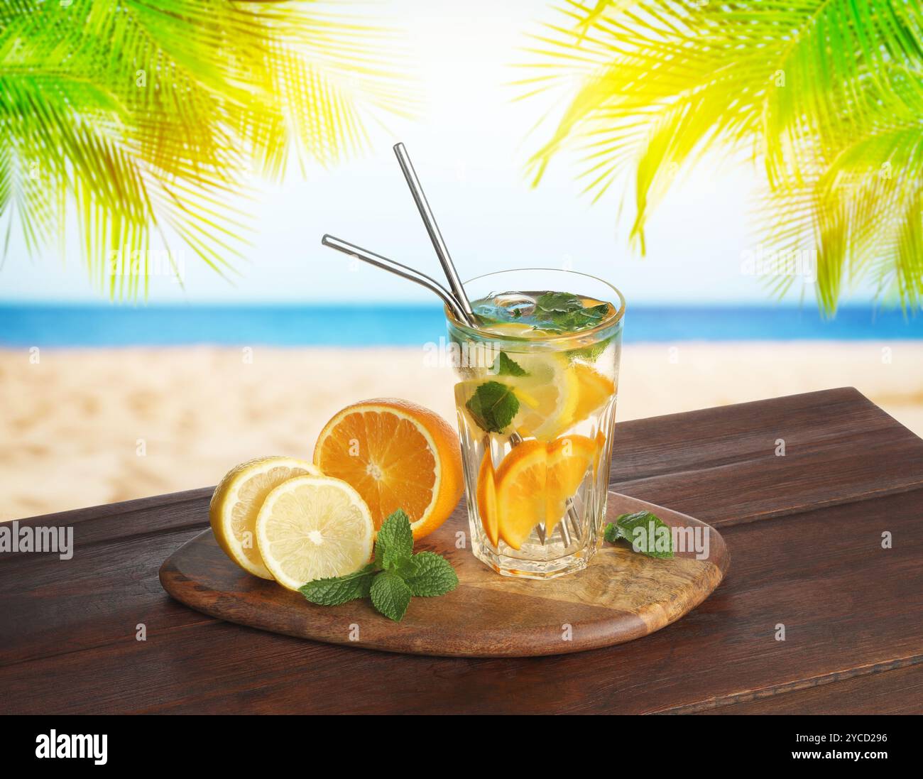 Bevanda rinfrescante con cannucce e agrumi freschi su un tavolo di legno in spiaggia Foto Stock