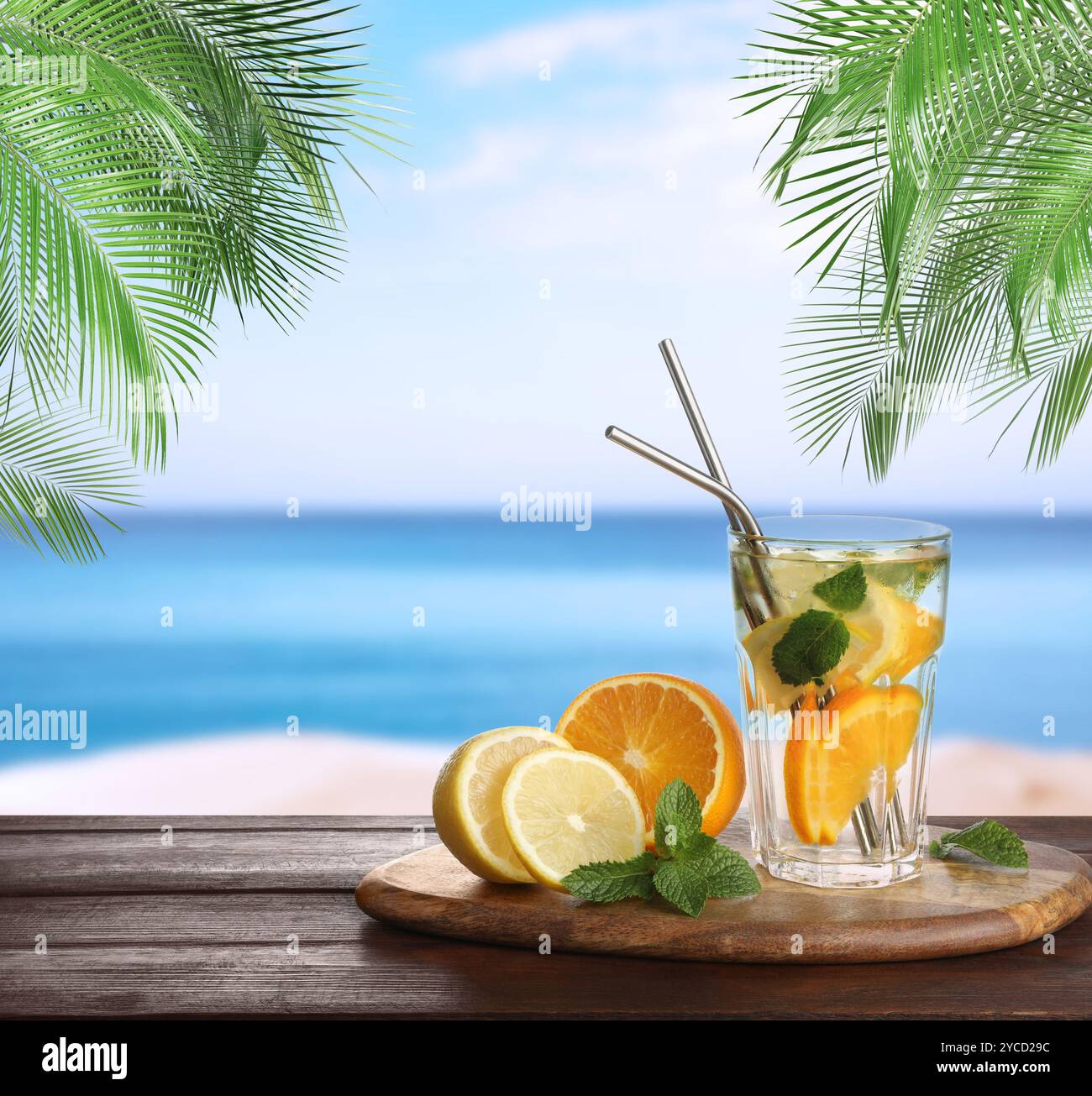 Bevanda rinfrescante con cannucce e agrumi freschi su un tavolo di legno in spiaggia Foto Stock
