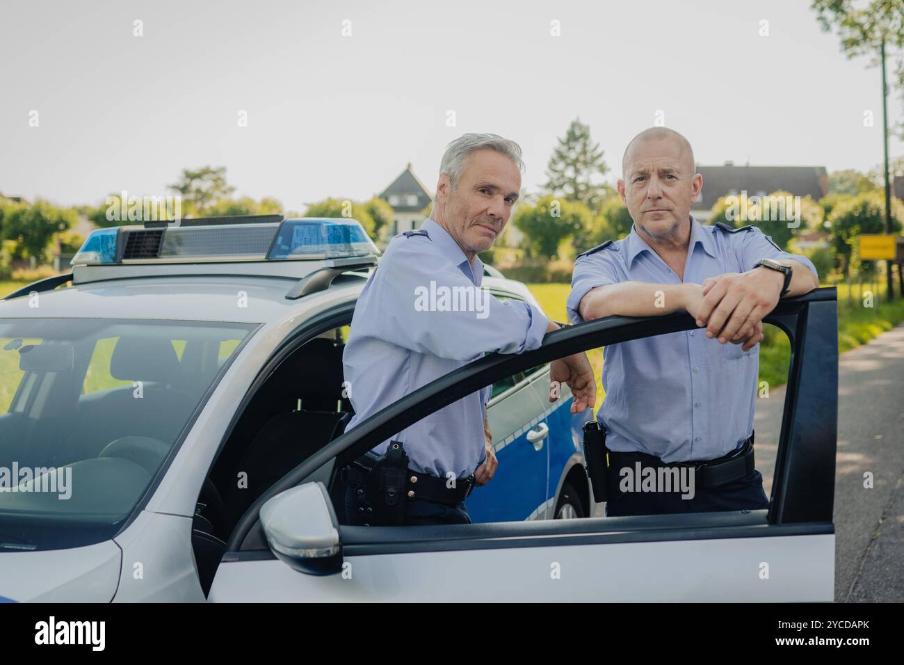 Colonia, Germania. 30 luglio 2024. Gli attori Heino Ferch (r) e Hannes Jaenicke stanno di fronte a un'auto della polizia durante le riprese. I due attori appaiono insieme davanti alla telecamera per la prima volta per la commedia ARD "Smeilingen". Credito: Marius Becker/dpa/Alamy Live News Foto Stock
