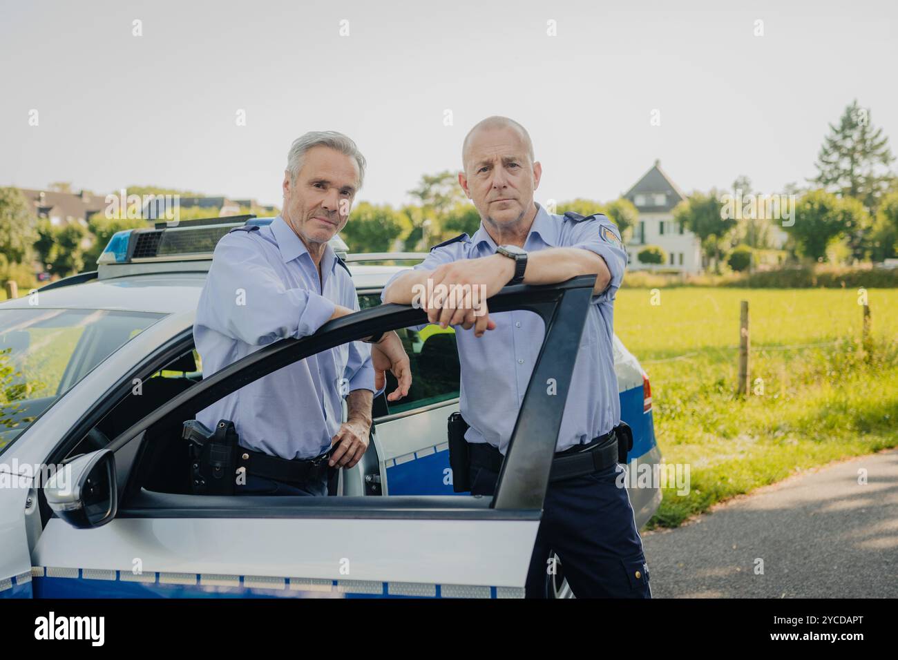 Colonia, Germania. 30 luglio 2024. Gli attori Heino Ferch (r) e Hannes Jaenicke stanno di fronte a un'auto della polizia durante le riprese. I due attori appaiono insieme davanti alla telecamera per la prima volta per la commedia ARD "Smeilingen". Credito: Marius Becker/dpa/Alamy Live News Foto Stock