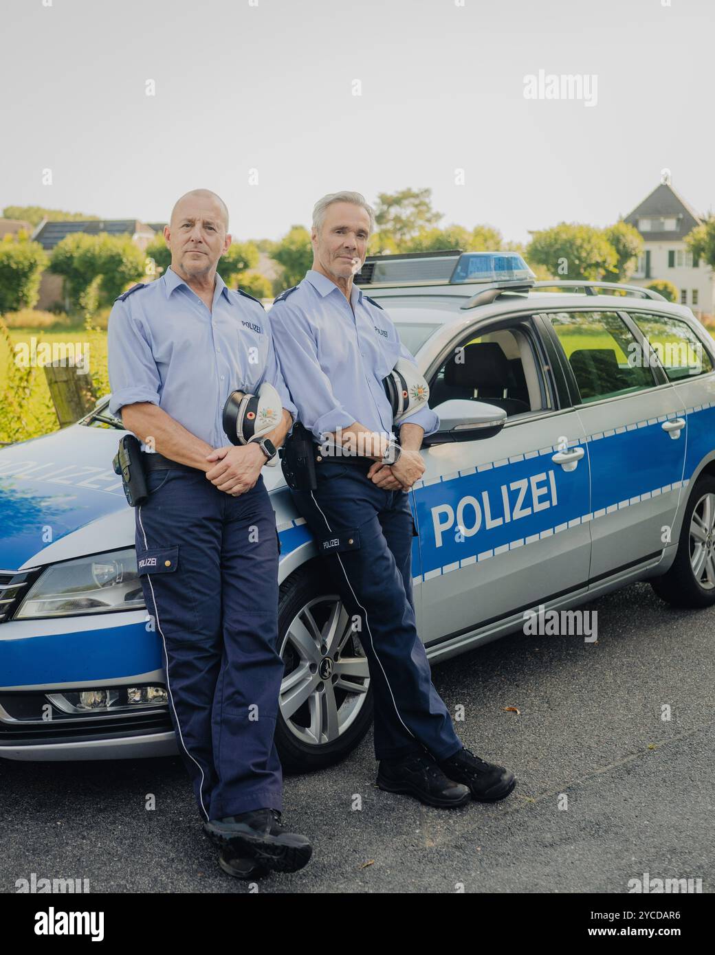 Colonia, Germania. 30 luglio 2024. Gli attori Heino Ferch (l) e Hannes Jaenicke stanno di fronte a un'auto della polizia durante le riprese. I due attori appaiono insieme davanti alla telecamera per la prima volta per la commedia ARD "Smeilingen". Credito: Marius Becker/dpa/Alamy Live News Foto Stock
