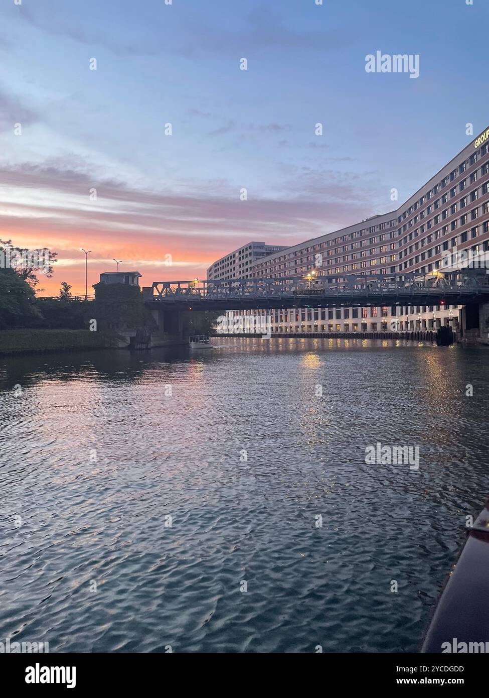 Il tramonto dipinge il fiume Chicago in oro liquido, mentre le infinite finestre dell'iconico Merchandise Mart rispecchiano l'ardente addio del cielo a un'altra giornata urbana. - Immagine stock catturata con smartphone