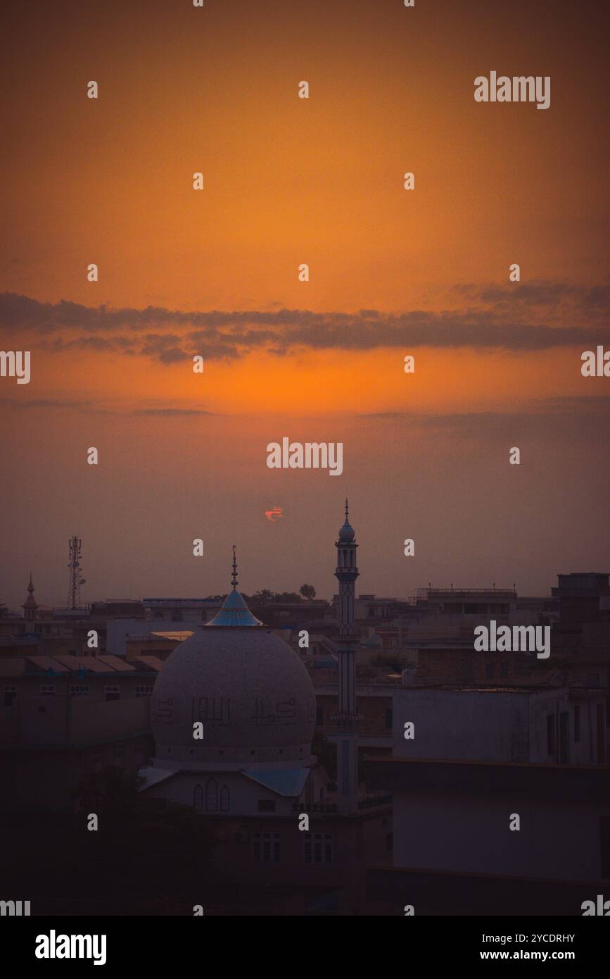 Uno splendido tramonto bagna il cielo di arancione, con uccelli che si innalzano sopra la silhouette di una moschea, creando un perfetto momento di tranquillità. #Sunset #Moschea Foto Stock