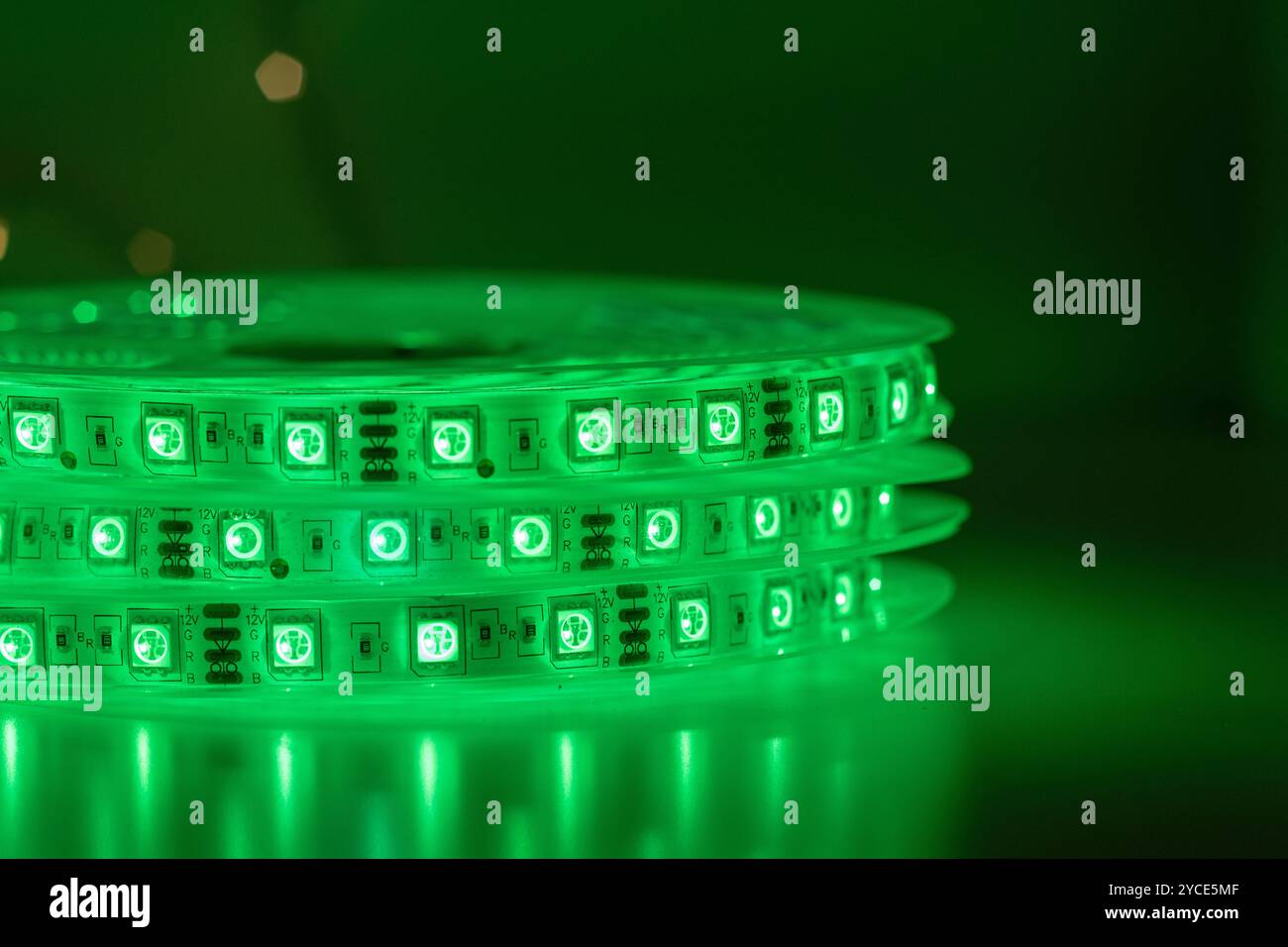 Bobina con rotolo di strisce luminose LED luminose posizionate sul tavolo, colore verde nelle stanze scure Foto Stock
