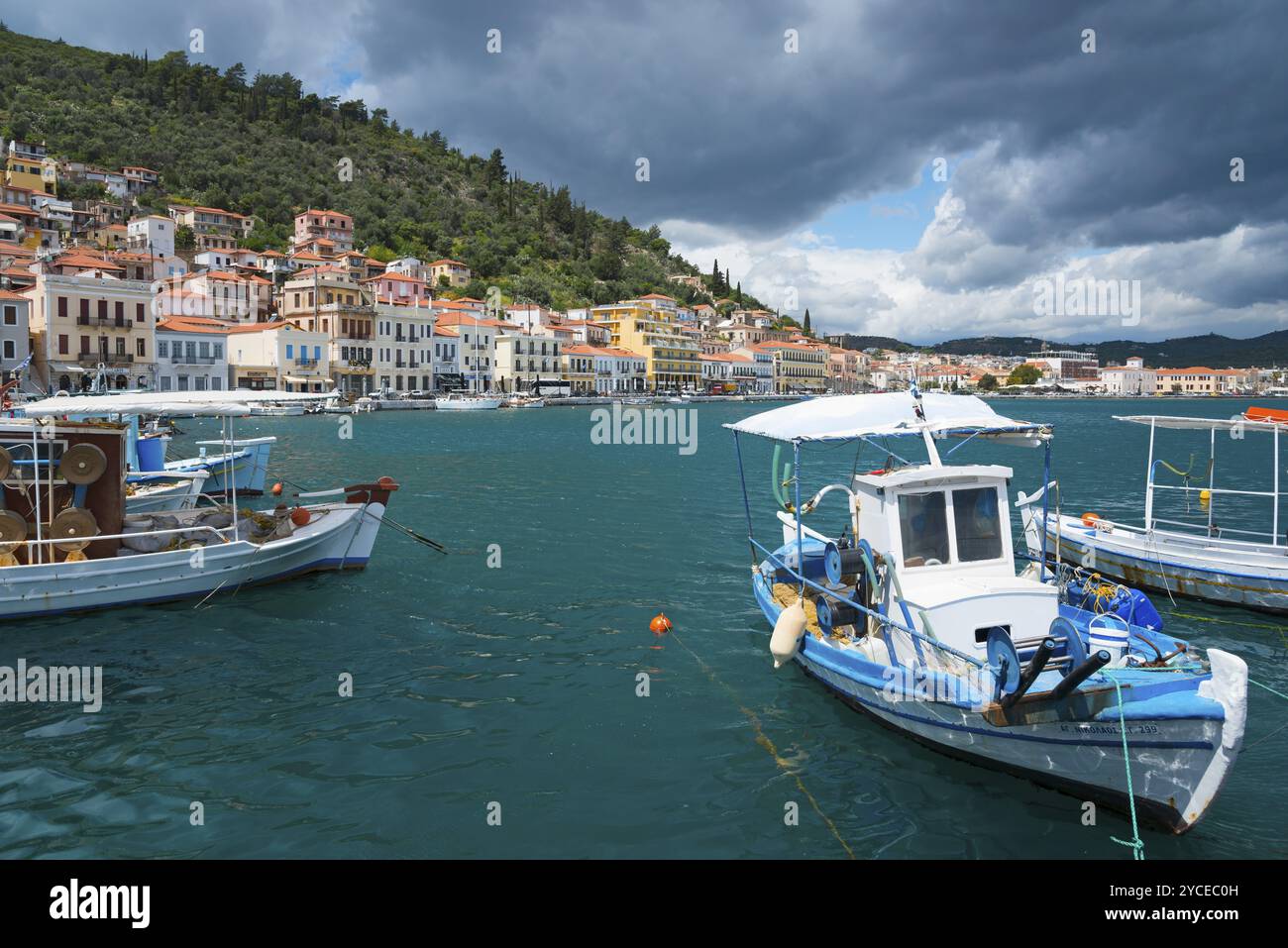 Città portuale con imbarcazioni in primo piano e una serie di colline boscose sullo sfondo sotto un cielo nuvoloso, Harbour, Gythio, mani, Laconia, Peloponn Foto Stock