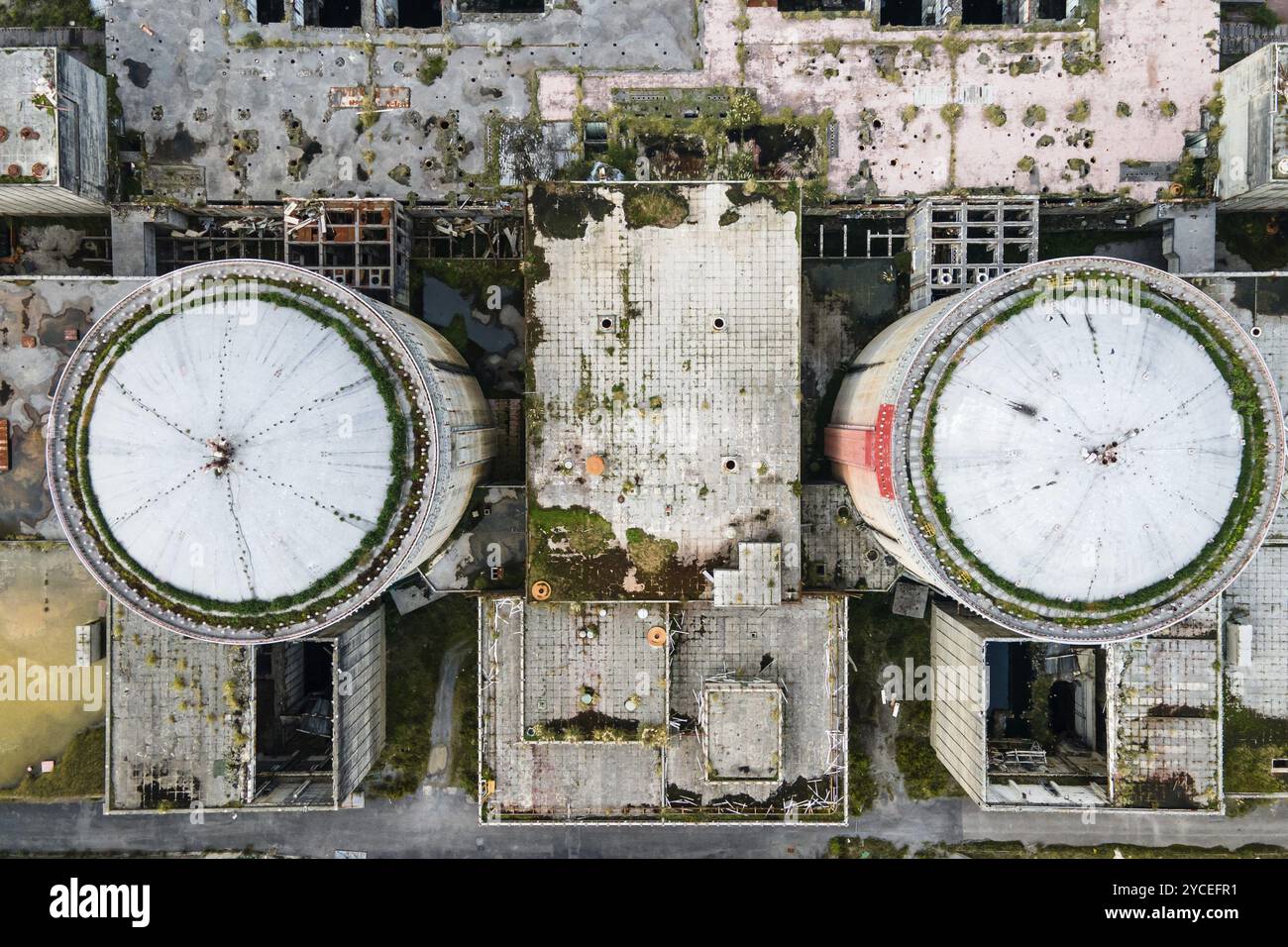 Vista aerea dal drone della centrale nucleare abbandonata e in rovina, torre rotonda del reattore atomico, grande edificio industriale demolito. Foto Stock