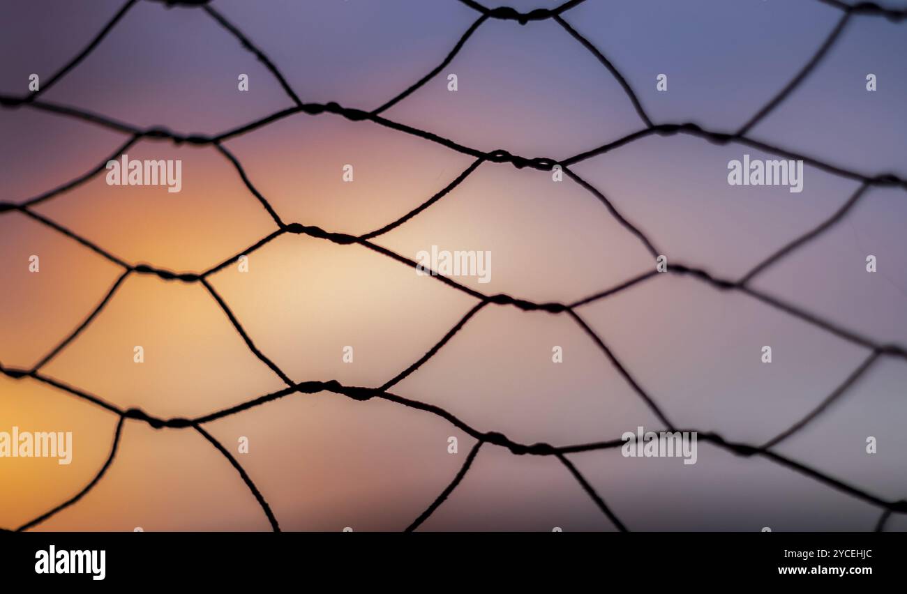 Profondità di campo bassa e primo piano su una vecchia recinzione all'alba con bei colori sullo sfondo Foto Stock