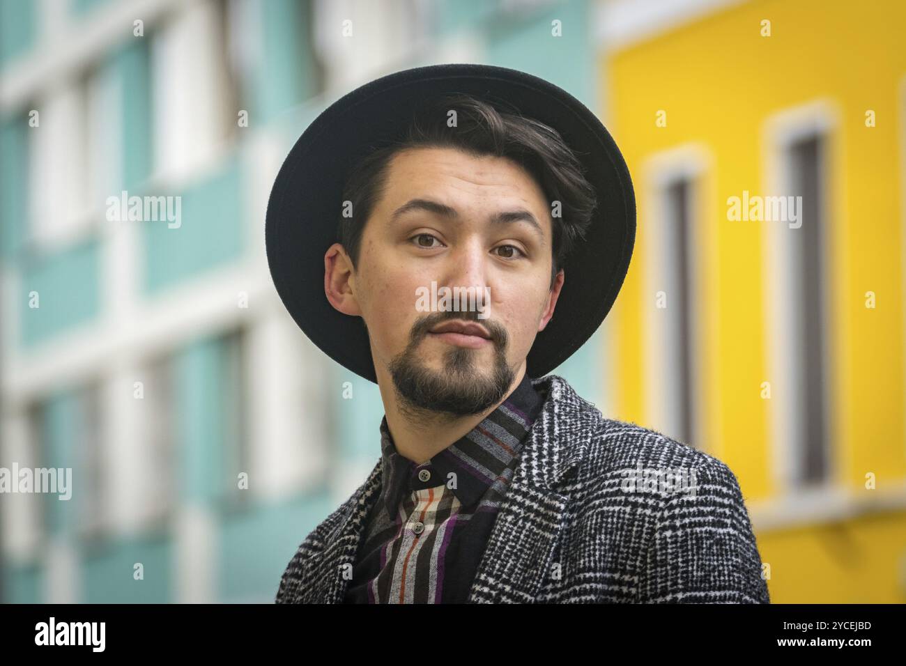 Ritratto di un giovane elegante e affascinante con un cappotto all'aperto. Un uomo serio che indossa un cappotto, un cappello e una camicia che guarda con sicurezza la fotocamera Foto Stock