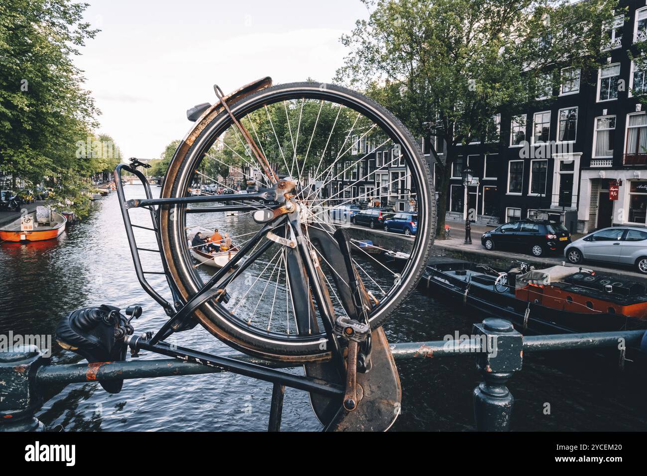 Amsterdam, Paesi Bassi, 09 agosto 2016. Vista sul canale di Amsterdam, vista attraverso la ruota in bicicletta parcheggiata sul ponte. Giorno d'estate Foto Stock