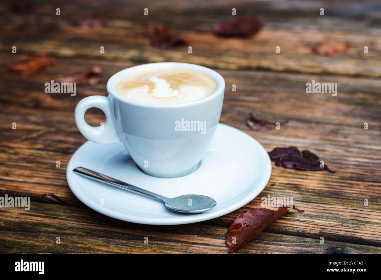 Una tazza di caffè su un tavolo di legno con foglie d'autunno marroni. Primo piano. Foto Stock
