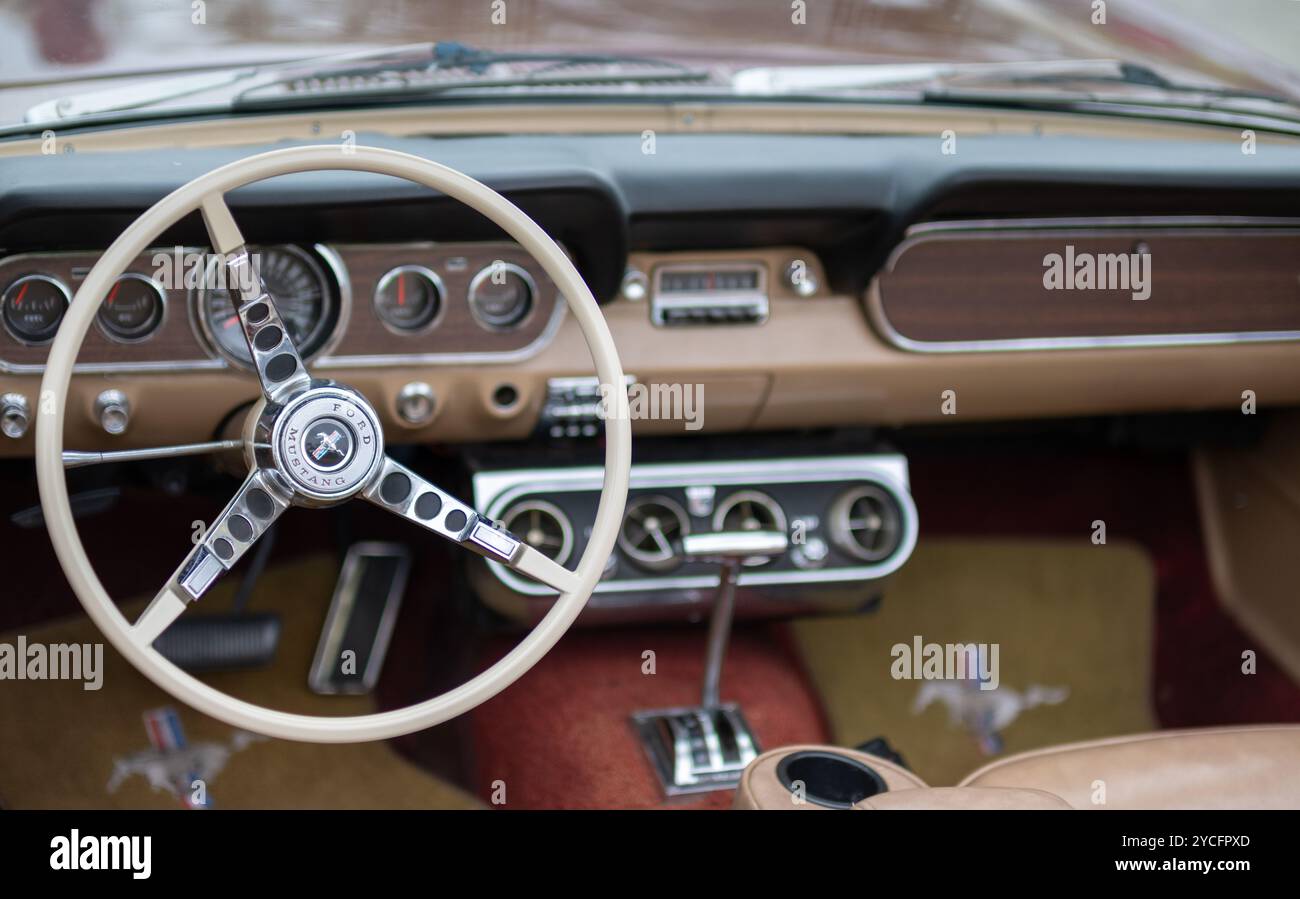 Vista interna di una Ford Mustang classica caratterizzata dal design iconico del volante e del cruscotto, che mostra lo stile automobilistico vintage. Foto Stock