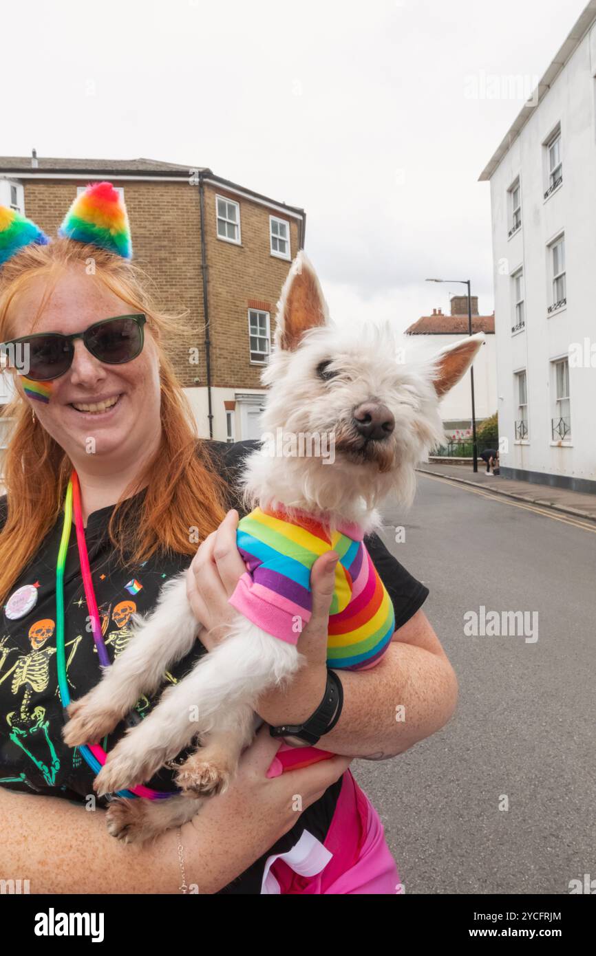 Inghilterra, Kent, Deal, Deal Pride Festival, donna che tiene in mano un cane che indossa un maglione colorato Pride Foto Stock