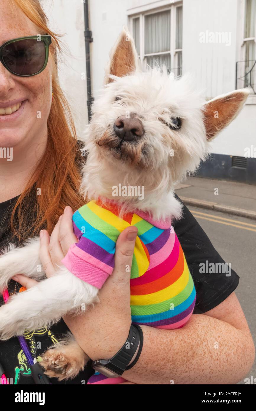 Inghilterra, Kent, Deal, Deal Pride Festival, donna che tiene in mano un cane che indossa un maglione colorato Pride Foto Stock