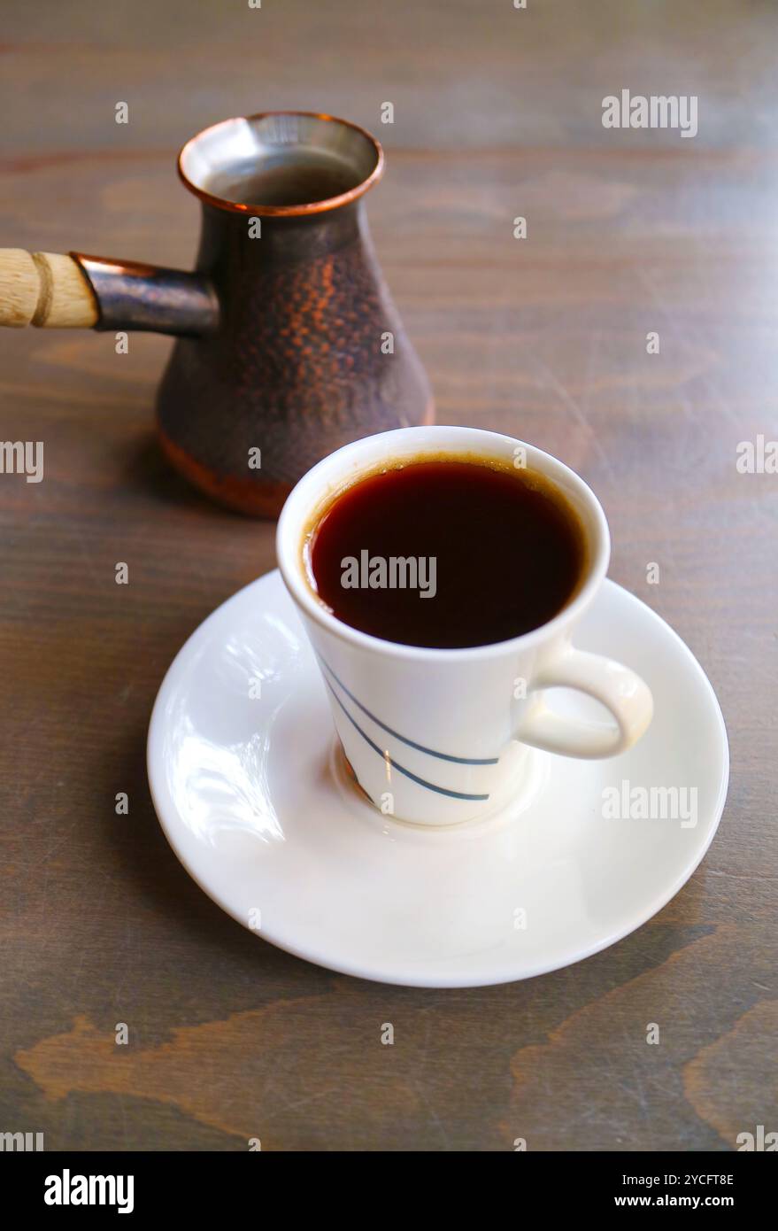 Tazza di caffè turco caldo con caldaia servita su un tavolo di legno Foto Stock