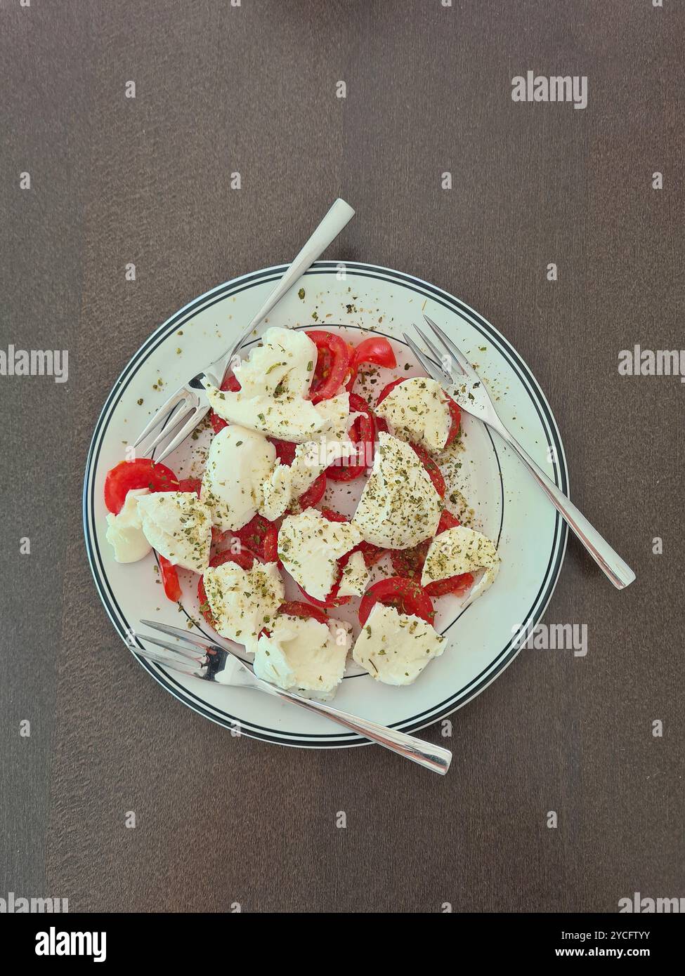 Mozzarella condita con pomodori e 3 forchette su un piatto bianco come antipasto per tre persone Foto Stock