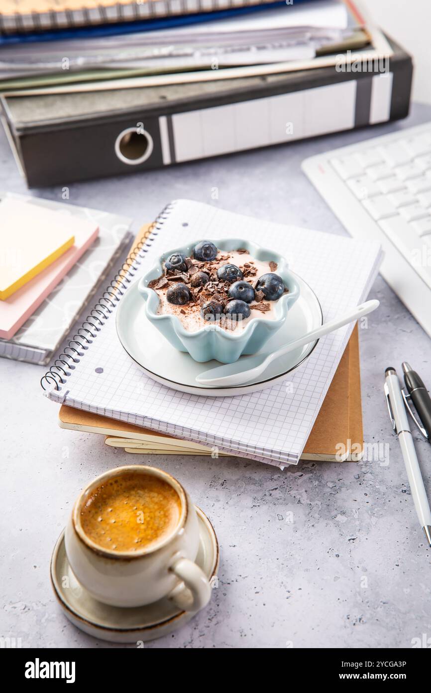 Pausa ufficio con caffè e yogurt sano con mirtilli Foto Stock