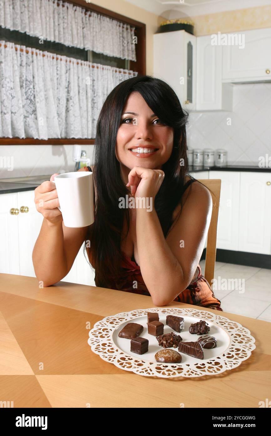 Una donna si vizia con il caffè e il decadente tartufo al cioccolato Foto Stock