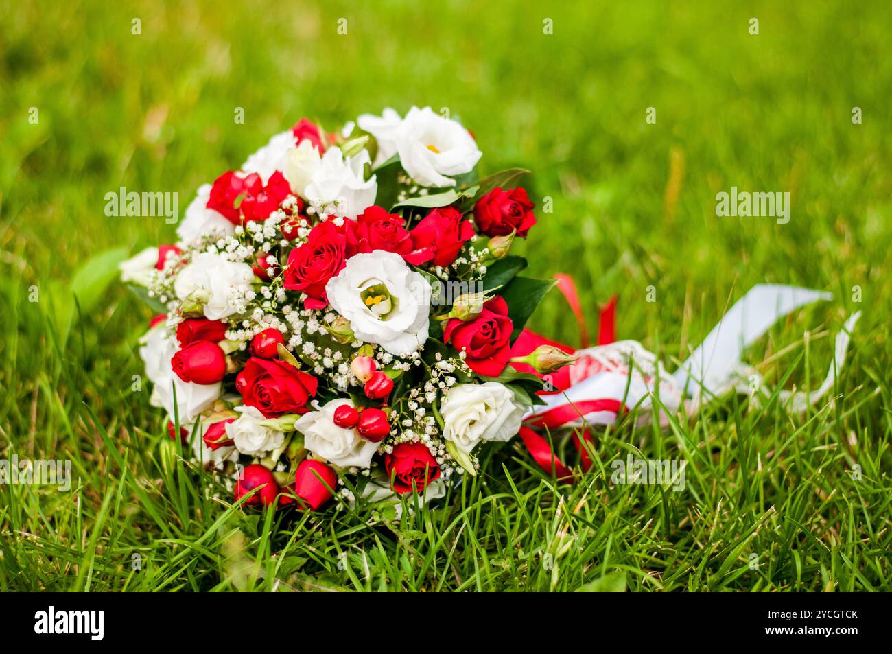 Vivace bouquet floreale adornato con rose rosse e bianche su un lussureggiante sfondo verde. Foto Stock