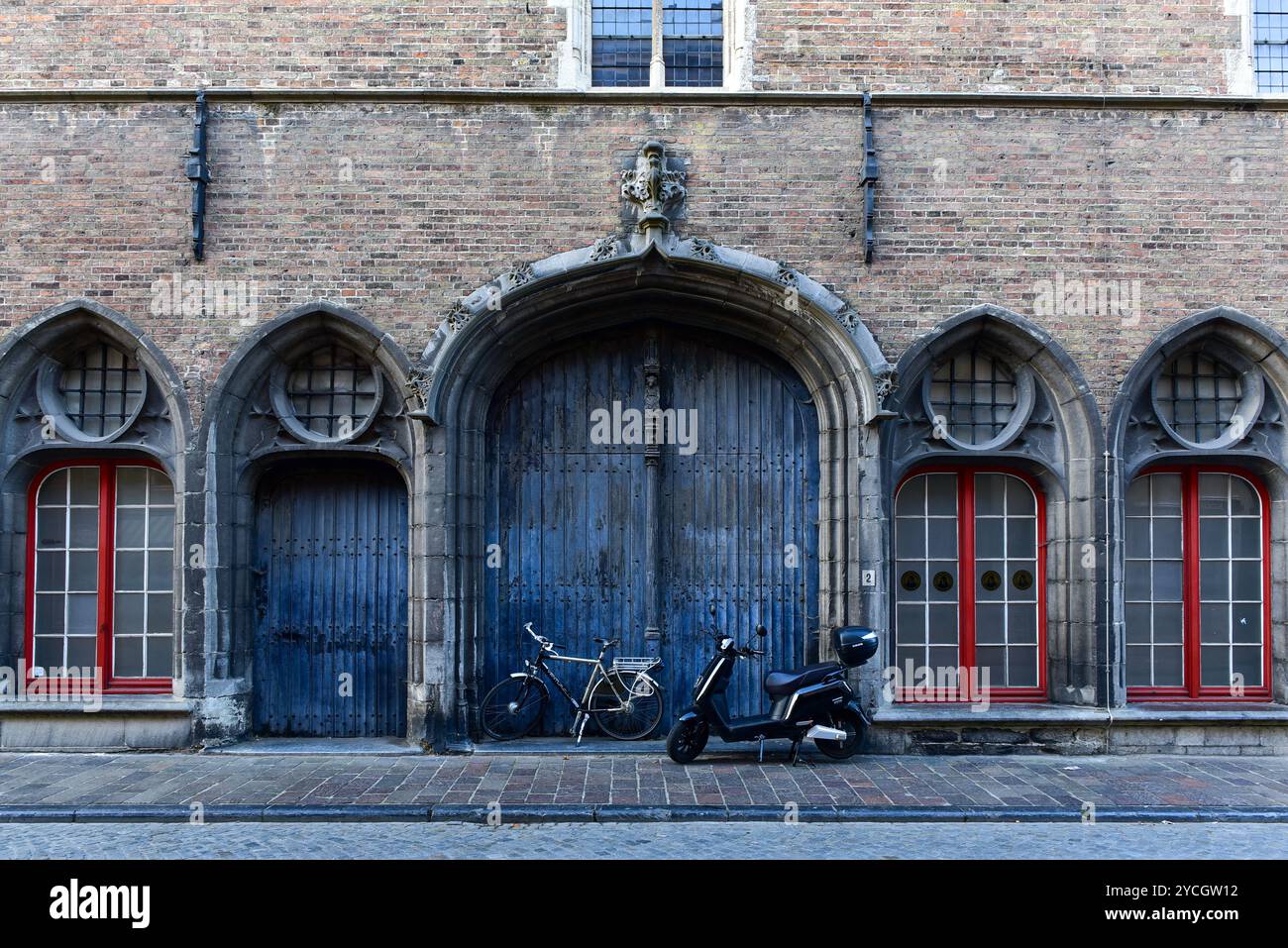Finestre con davanzali dipinte in rosso e cancello ad arco in blu sbiadito sul lato rivolto verso Wollestraat del Belfry di Bruges, Belgio Foto Stock