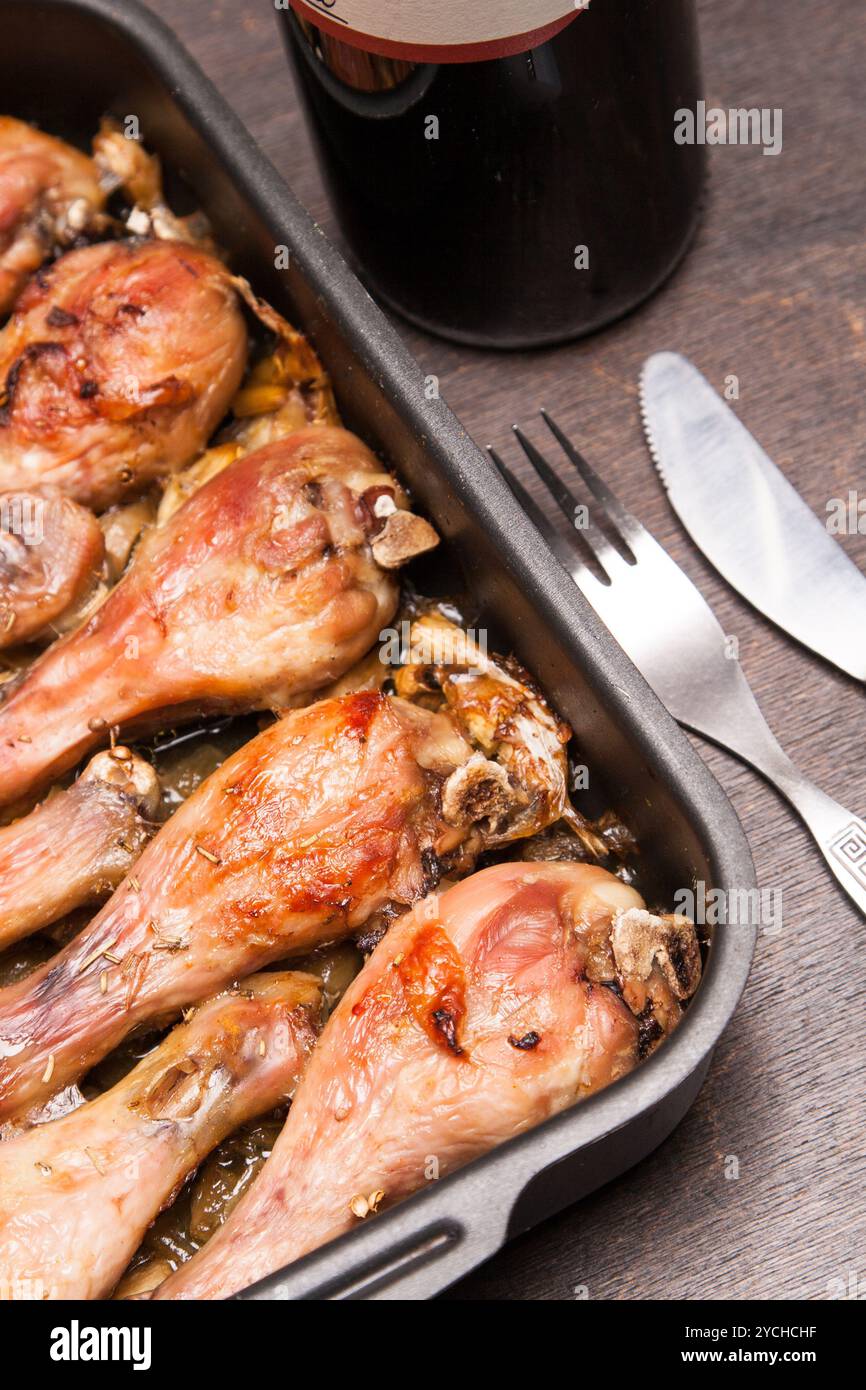 Cosce di pollo cotte in vassoio su legno nero Foto Stock