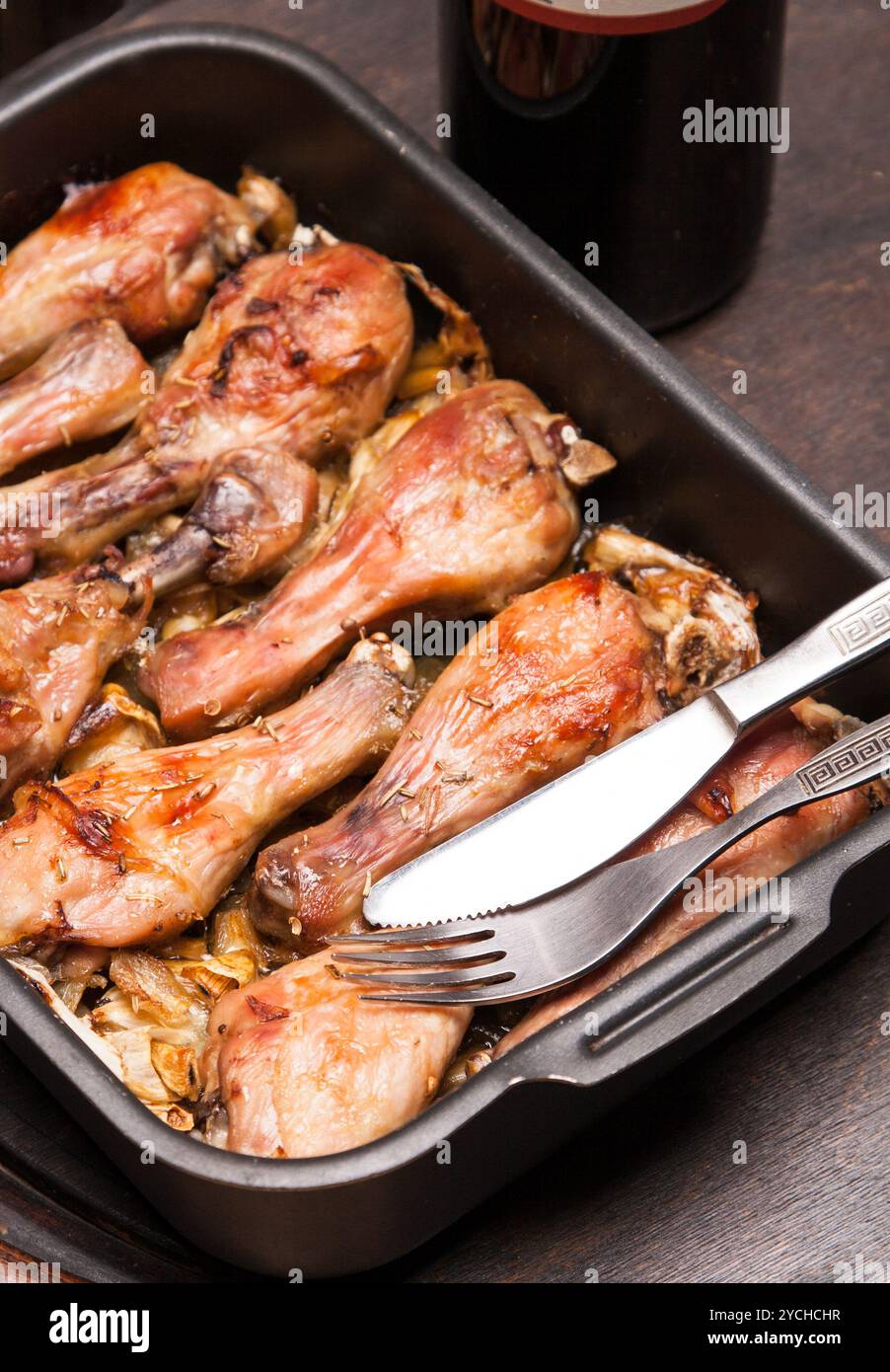 Cotte le cosce di pollo nel vassoio sul nero lo sfondo di legno Foto Stock