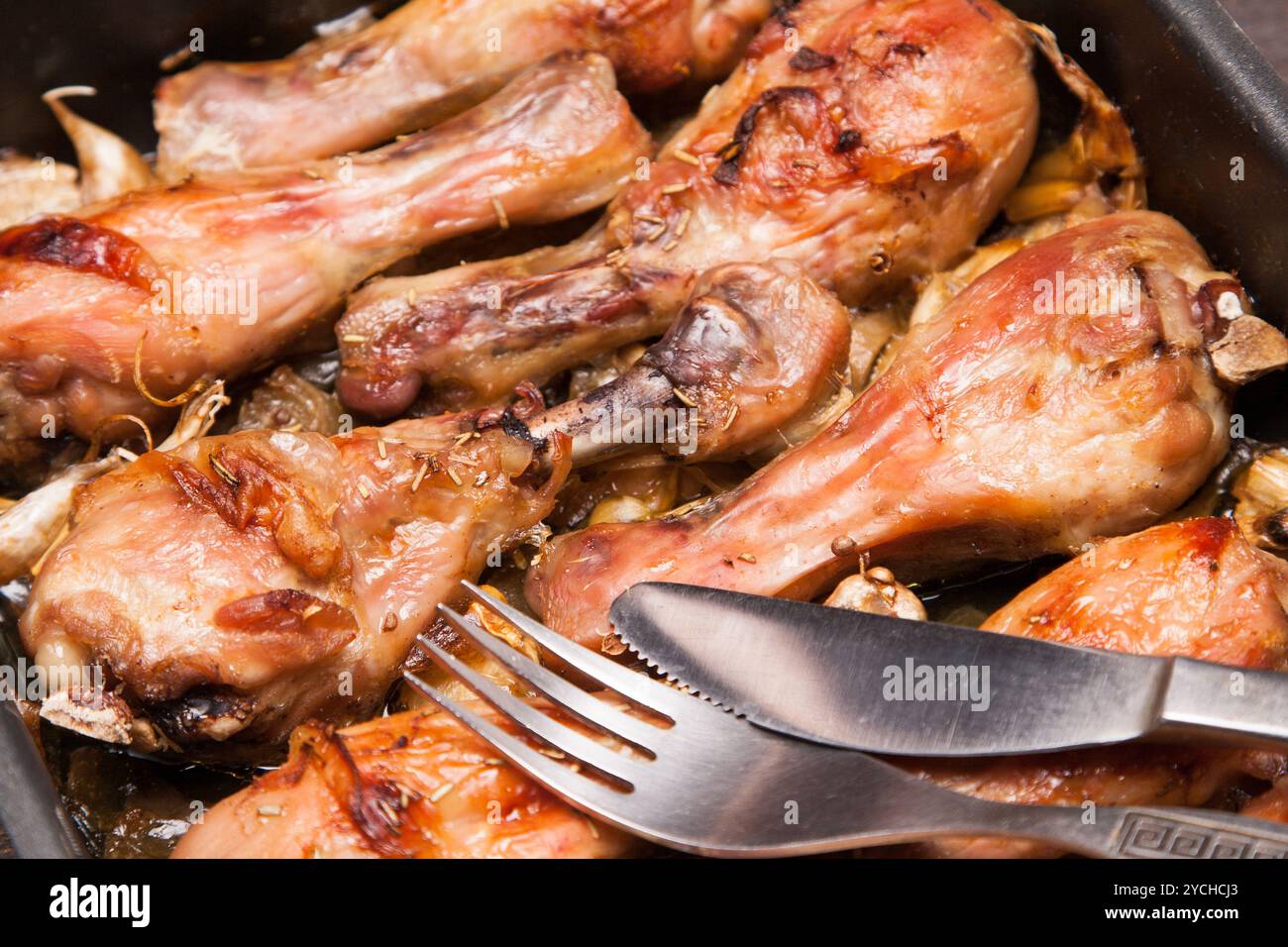 Cosce di pollo cotte in vassoio su legno nero Foto Stock