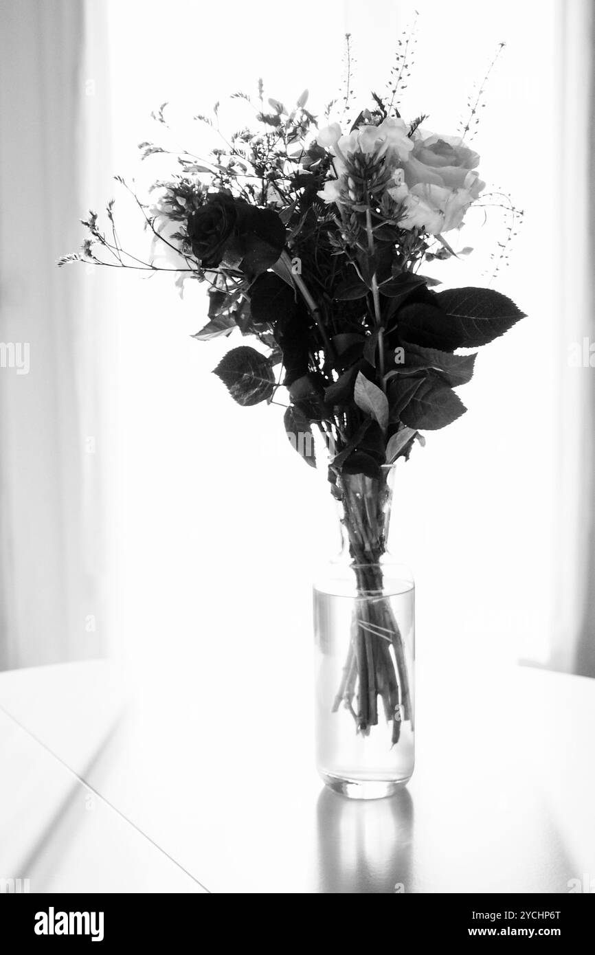 Basta un bellissimo bouquet di rose in un vaso posto su un tavolo con una splendida luce autunnale contro la luce Foto Stock