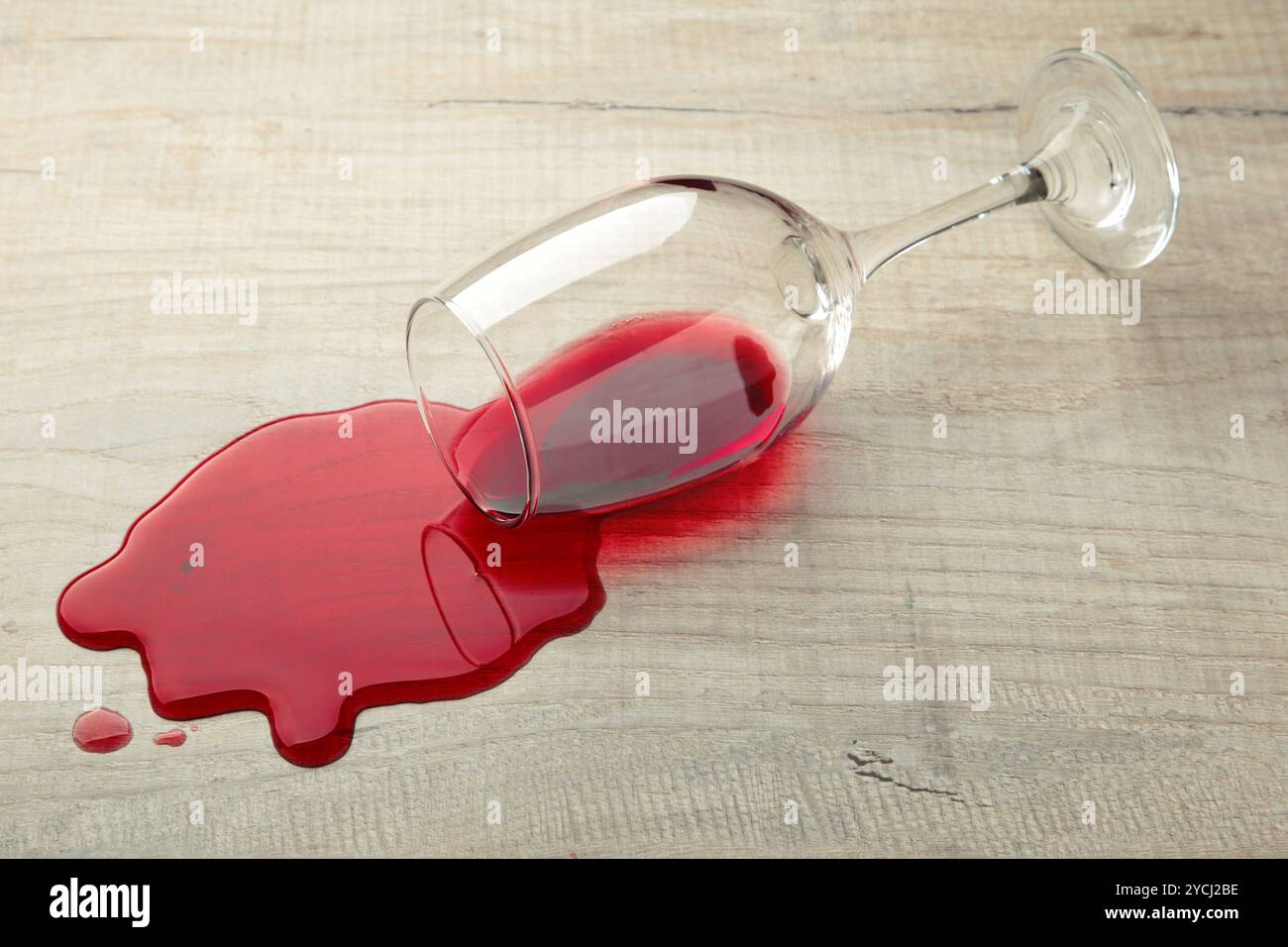Un bicchiere di vino rosso è caduto sul laminato, il vino è versato sul pavimento. Vista dall'alto Foto Stock