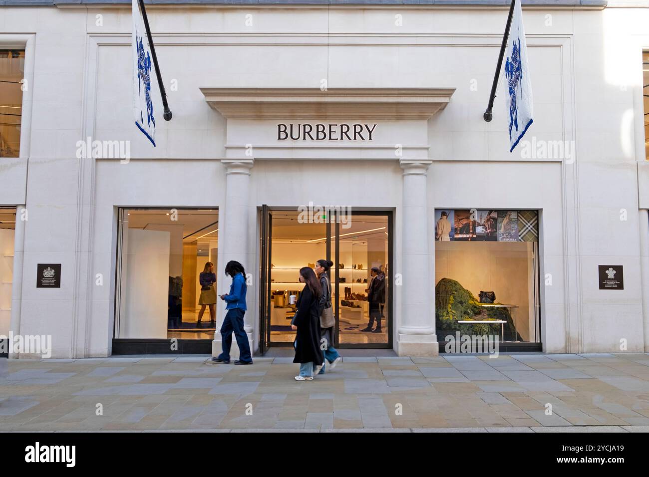 Persone che fanno acquisti che passano davanti a loro e guardano la vetrina del negozio Burberry in ond Street nell'autunno di ottobre 2024 Londra Inghilterra Regno Unito KATHY DEWITT Foto Stock