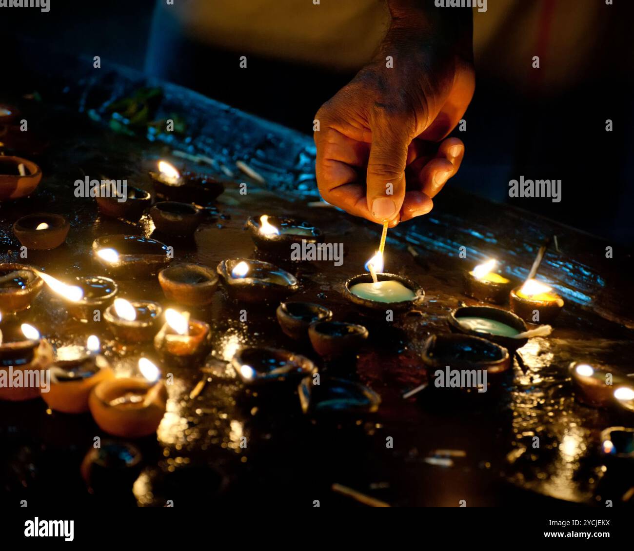 Persone che bruciano lampade a olio come rituale religioso Foto Stock
