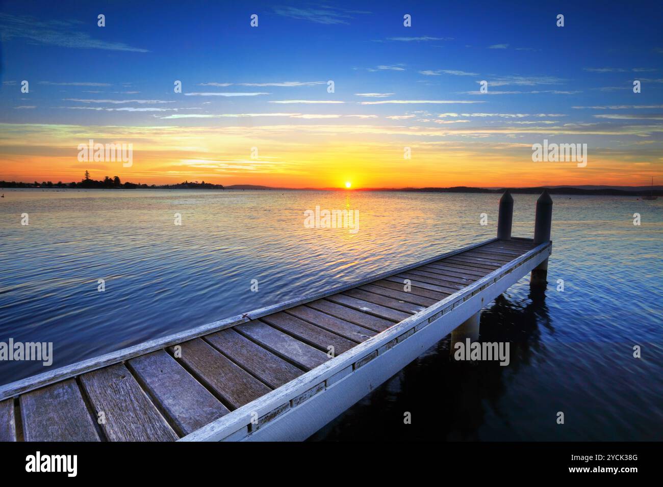 Sole che tramonta dietro il molo, Lago Maquarie Foto Stock