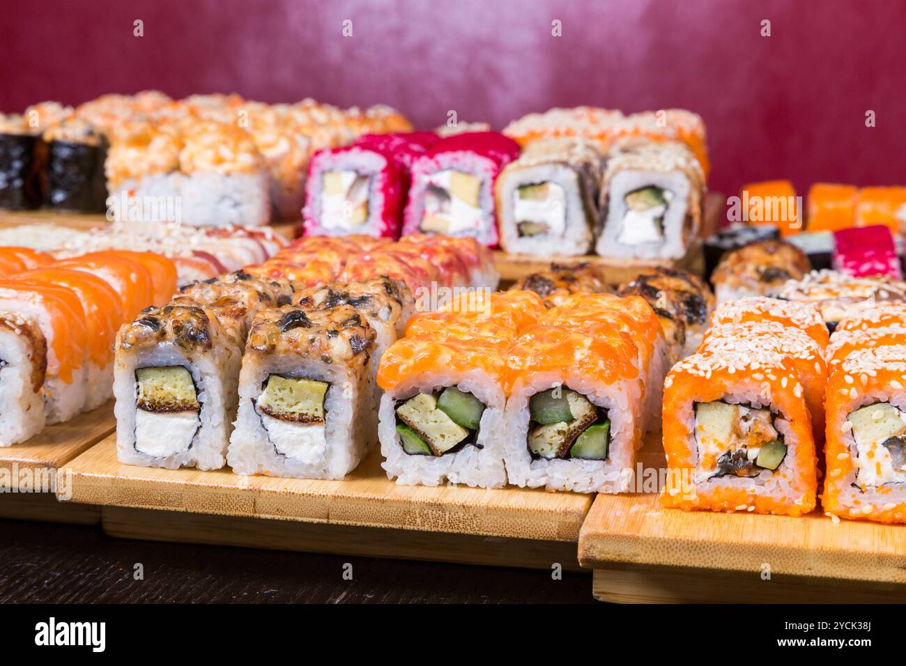 Sushi e panini assortiti su tavola di legno in luce buia Foto Stock